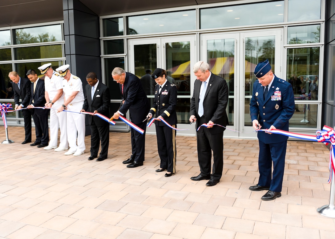 Officials representing the five residing agencies at the Russell Knox Building cut the ribbon to officially commemorate the grand opening of the facility at Marine Corps Base Quantico, Va., Sept. 19. They were joined by representatives for the agencies who held key roles in the construction of the building. (U.S. Air Force Photo by Mike Hastings.)