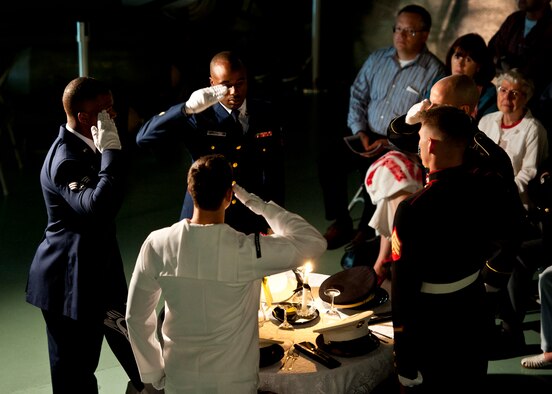 Joint-service honor guard members salute at the POW/MIA table setting during the POW/MIA ceremony Sept. 16 at the Air Force Armament Museum. The ceremony paid tribute to those military members who have yet to return home from defending America. The event was hosted by the 46th Test Wing and featured guest speakers, honor guard procedures and a flyover by the 53rd Wing. (U.S. Air Force photo/Samuel King Jr.)