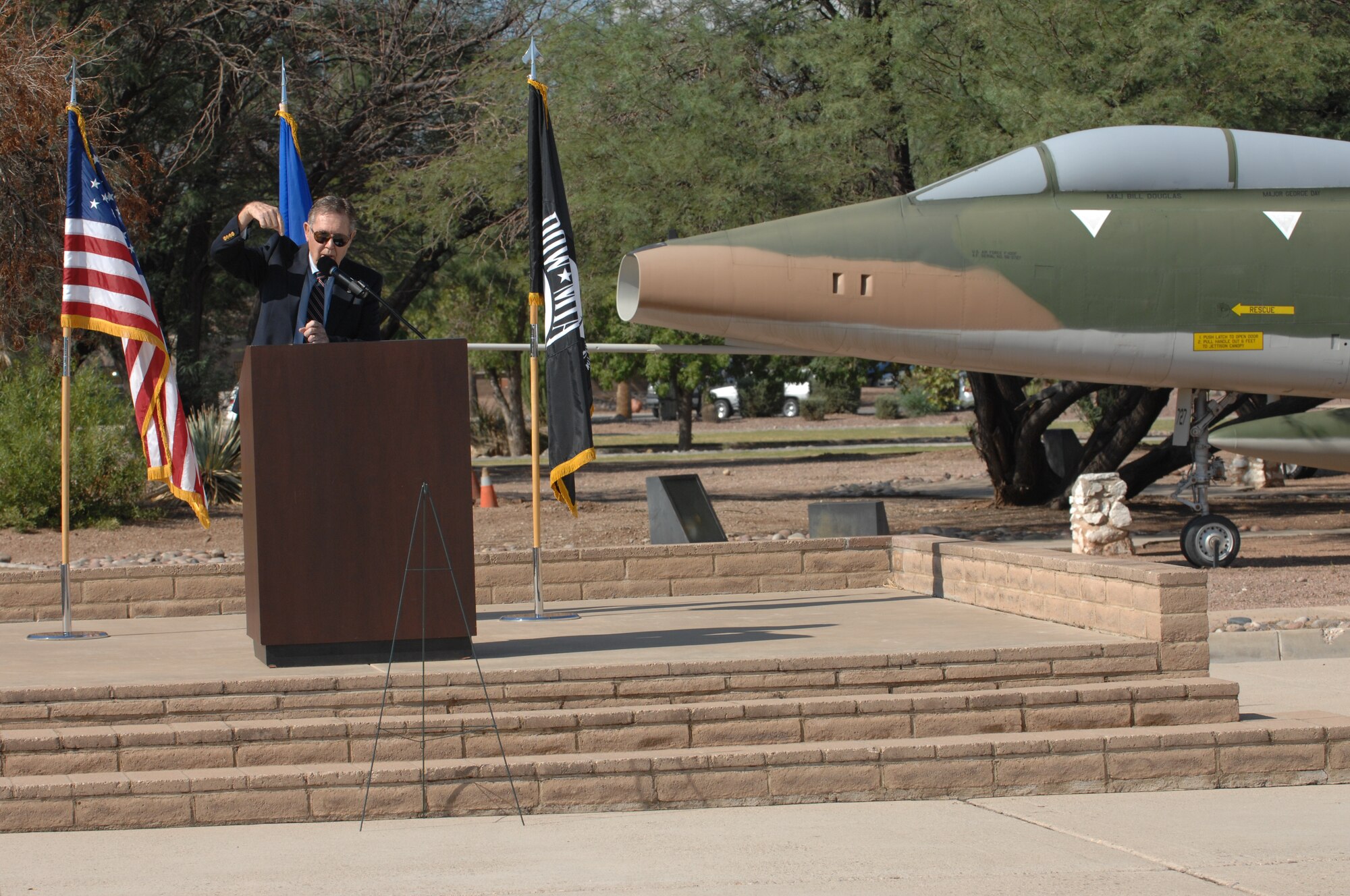 DAVIS-MONTHAN AIR FORCE BASE, Ariz. – Col. (Ret.) Robert Barnett speaks at the prisoner of war/missing in action remembrance ceremony here Sept. 16. Barnett, a former fighter pilot and Vietnam War POW, piloted the A-7 Corsair II (pictured in background). (U.S. Air Force photo/Airman 1st Class Timothy D. Moore)