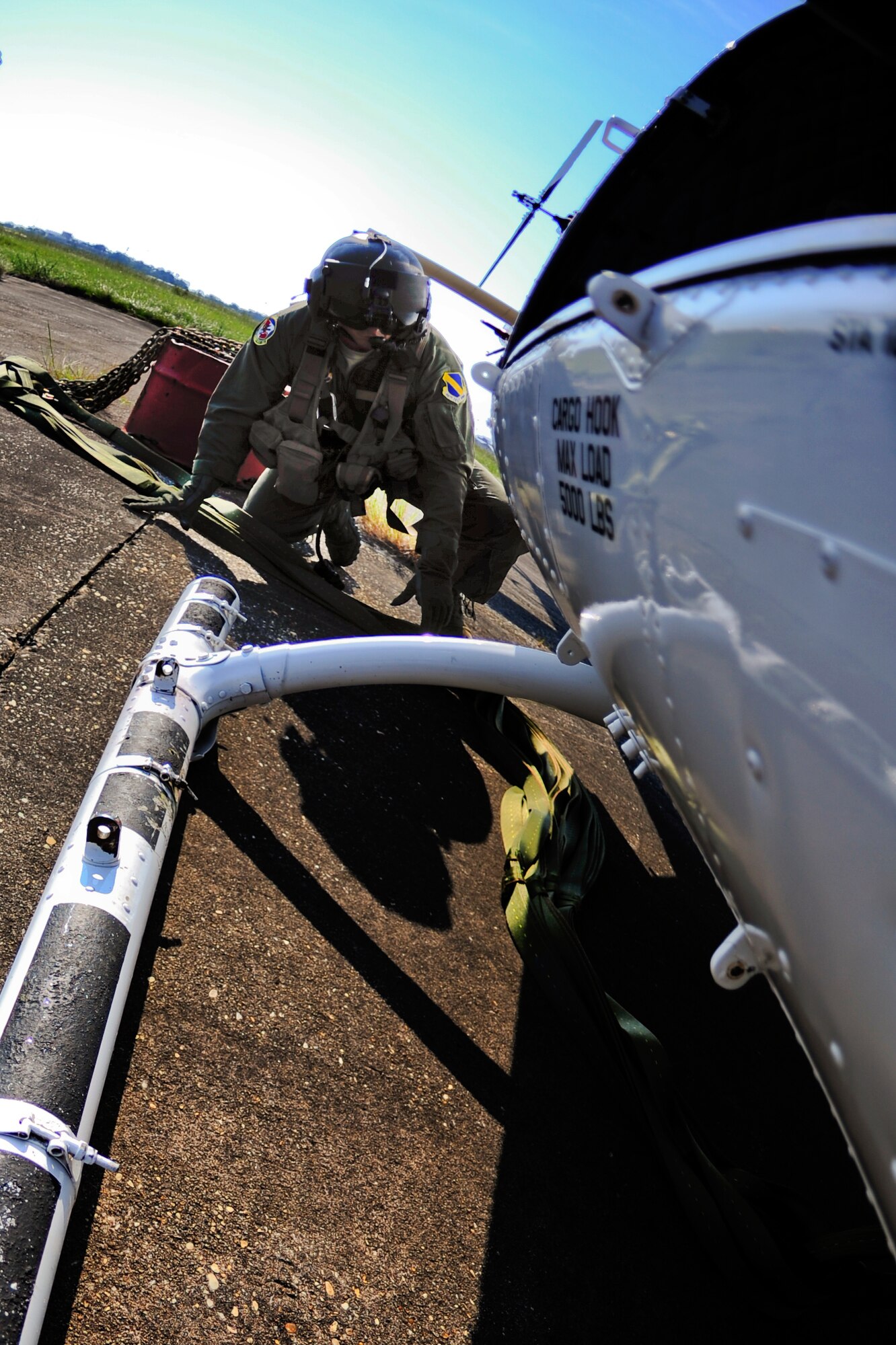 Tech. Sgt. James Kempfer, 40th Flight Test Squadron Flight Engineer, crawls under the UH-1 Huey to connect the cargo sling during a training mission at Eglin Air Force Base, Fla., Sept. 15.  The cargo sling is capable of carrying up to 5000 pounds of cargo.  (U.S. Air Force photo/Staff Sgt. Joely Santiago)