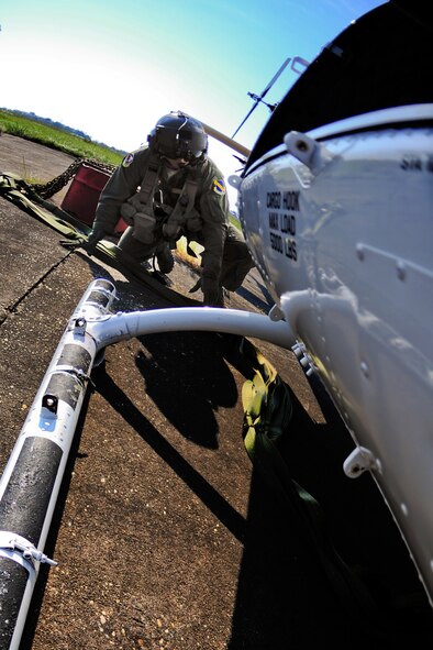 Tech. Sgt. James Kempfer, 40th Flight Test Squadron Flight Engineer, crawls under the UH-1 Huey to connect the cargo sling during a training mission at Eglin Air Force Base, Fla., Sept. 15.  The cargo sling is capable of carrying up to 5000 pounds of cargo.  (U.S. Air Force photo/Staff Sgt. Joely Santiago)