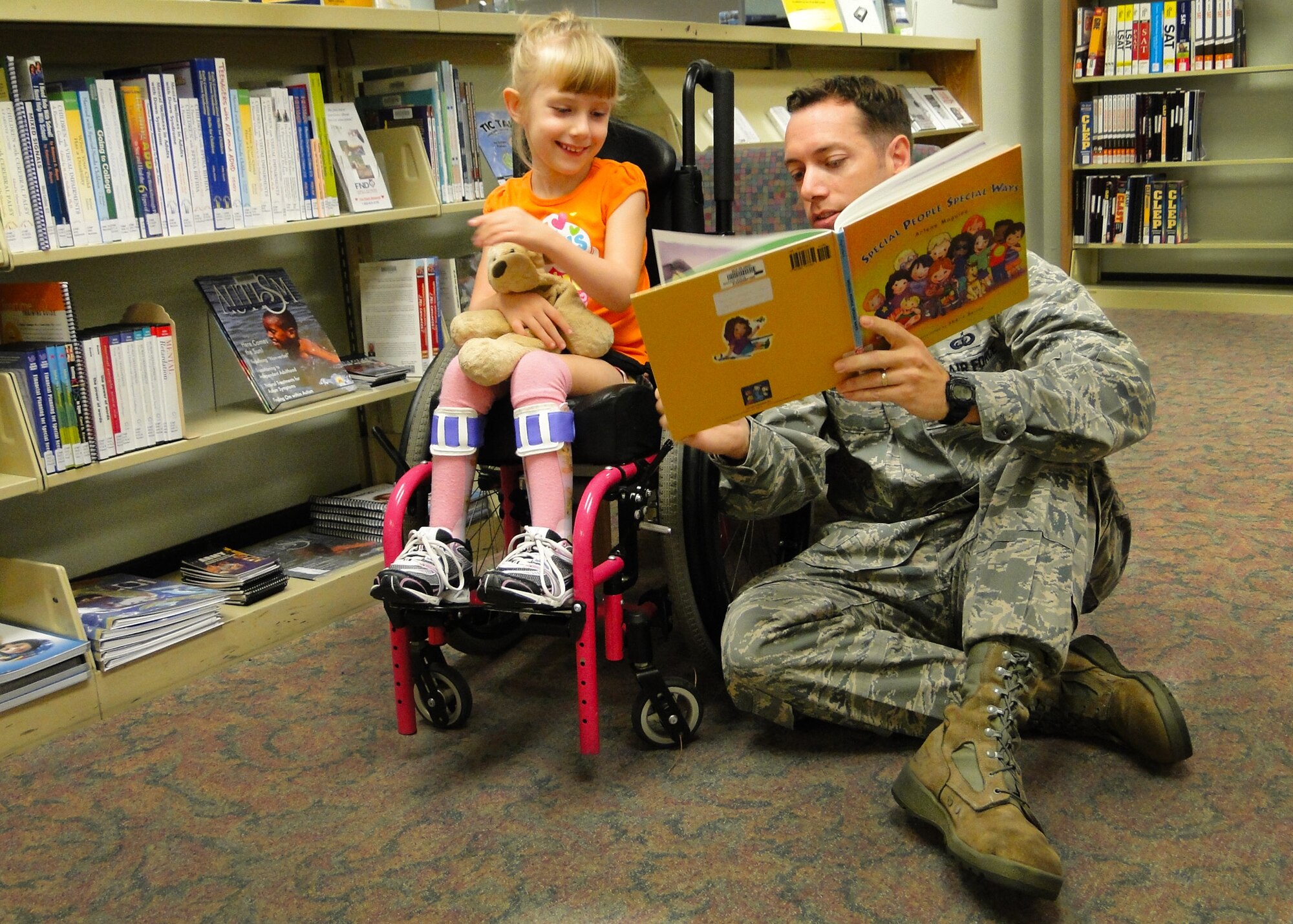 Maj. Jason Delamater, the 96th Force Support Squadron commander, reads to Madison Hennessey, at the unveiling of the new Special Needs collection targeting Exceptional Family Member Program families.  The new collection contains books and videos about a variety of Special Needs issues from financial planning to parenting.  (U.S. Air Force photo/Joshua Bausch)
 
