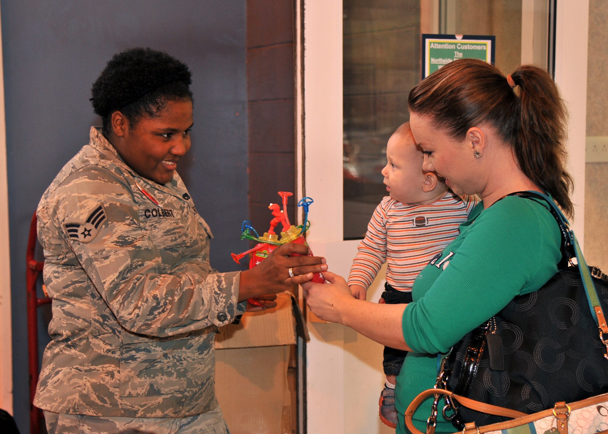 RAF MILDENHALL, England – Senior Airman Samantha Colbert, 100th Communications Squadron, hands a souvenir to 10-month-old Alexander Vargas and his mother Jennifer Vargas at the Sesame Street/USO Experience for Military Families show at the Northside Fitness Center here Sept. 15, 2011. The 2011 tour focused on the impact a military lifestyle has on children. (U.S. Air Force photo by Senior Airman Jerilyn Quintanilla)