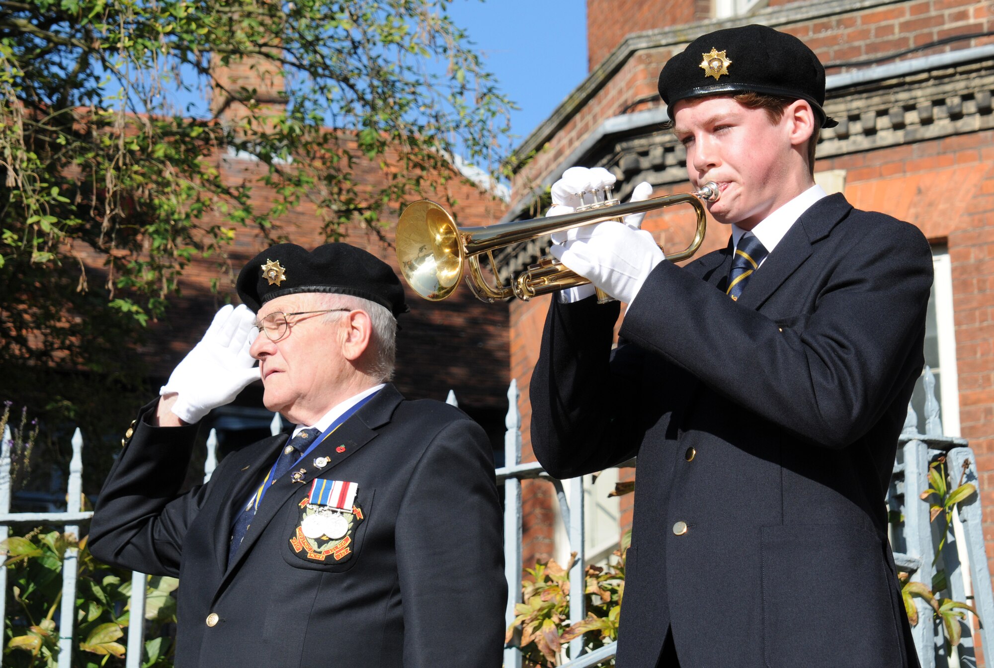 RAF MILDENHALL, England – A Royal Air Force Cadet plays his national anthem on a bugle while a World War II veteran, also a member of the Royal British Legion, salutes. The veterans later grouped into a formation and marched along with an active duty RAF Regiment, a formation of U.S. Airmen, and three formations of cadets. (U.S. Air Force photo/Tech. Sgt. Kevin Wallace)