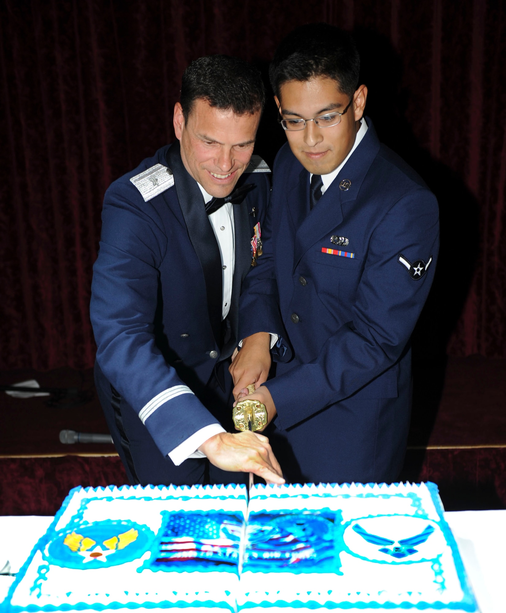 In celebration of the Air Force's 64th birthday the 18th Wing commander, Big. Gen. Mathew Malloy and Airman Roy De Jesus, 18th Communications Squadron, cuts a birthday cake with a saber during Kadena's Air Force Ball on Sept. 17, 2011. As per tradition, the oldest and youngest present Airman are the two to cut the cake. (U.S. Air Force photo by Airman 1st Class Brooke P. Beers)