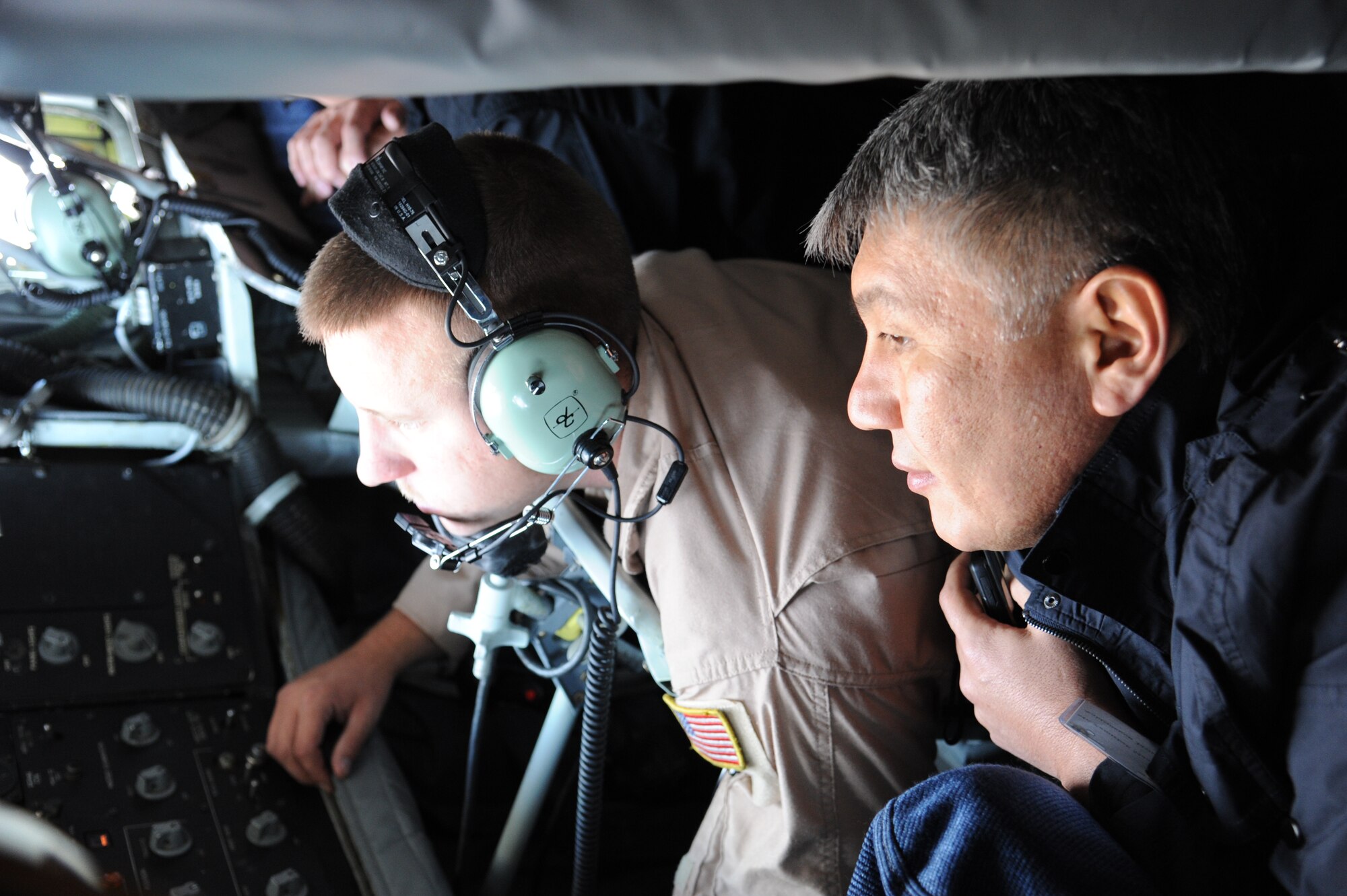 Members of the Kyrgyz Republic Parliament look on as Staff Sgt. Chad Holloway, 22nd Expeditionary Air Refueling Squadron boom operator, scans for an incoming aircraft during a KC-135 refueling familiarization flight over Kyrgyzstan Sept. 17. This high-level visit underpins Air Forces Central Command and U.S.  Central Command goals for sustained partnership building and cultivating enduring relationships in support of U.S. foreign policy objectives.  Holloway is deployed from the 92nd Air Refueling Squadron at Fairchild Air Force Base, Wash. (U.S. Air Force photo/Tech. Sgt. Hank Hoegen)