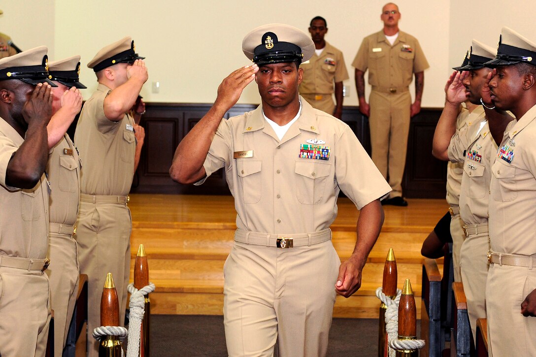 U.S. Navy Chief Petty Officer Corey B. Daniel salutes while walking past side boys during the Chief Petty Officer Pinning Ceremony at Commander, Fleet Activities Sasebo, Japan, Sept. 16, 2011. Daniel is an information technician assigned to Assault Craft Unit 5 and was one of 10 sailors advanced to the rank of chief petty officer during the ceremony.