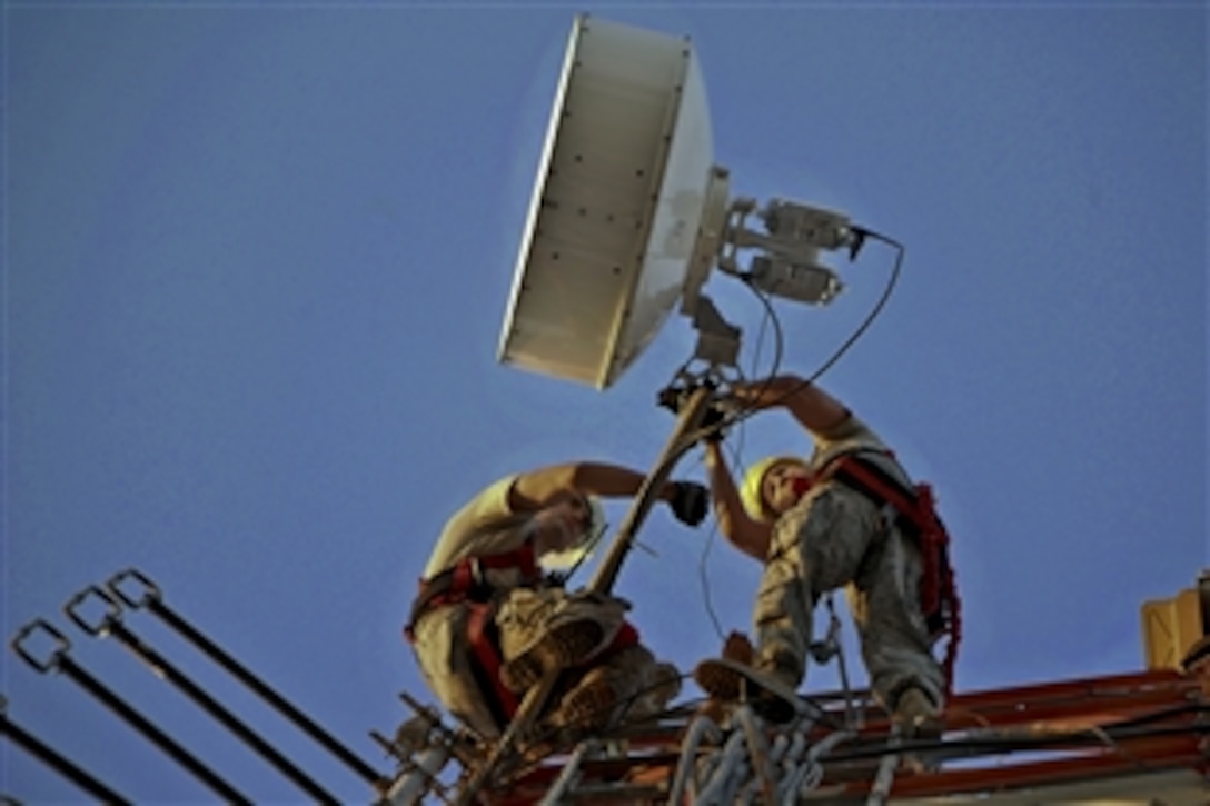 U.S. Air Force Airman 1st Class Steve Lippitt and Master Sgt. Todd Tripplett perch on a limb of a 140-foot communications tower to adjust the signal strength of a microwave antenna on Sather Air Base in Iraq, Sept. 13, 2011. Lippitt and Tripplett are technicians assigned to the 447th Expeditionary Communications Squadron. The microwave antenna will provide network access for U.S. State Department personnel.