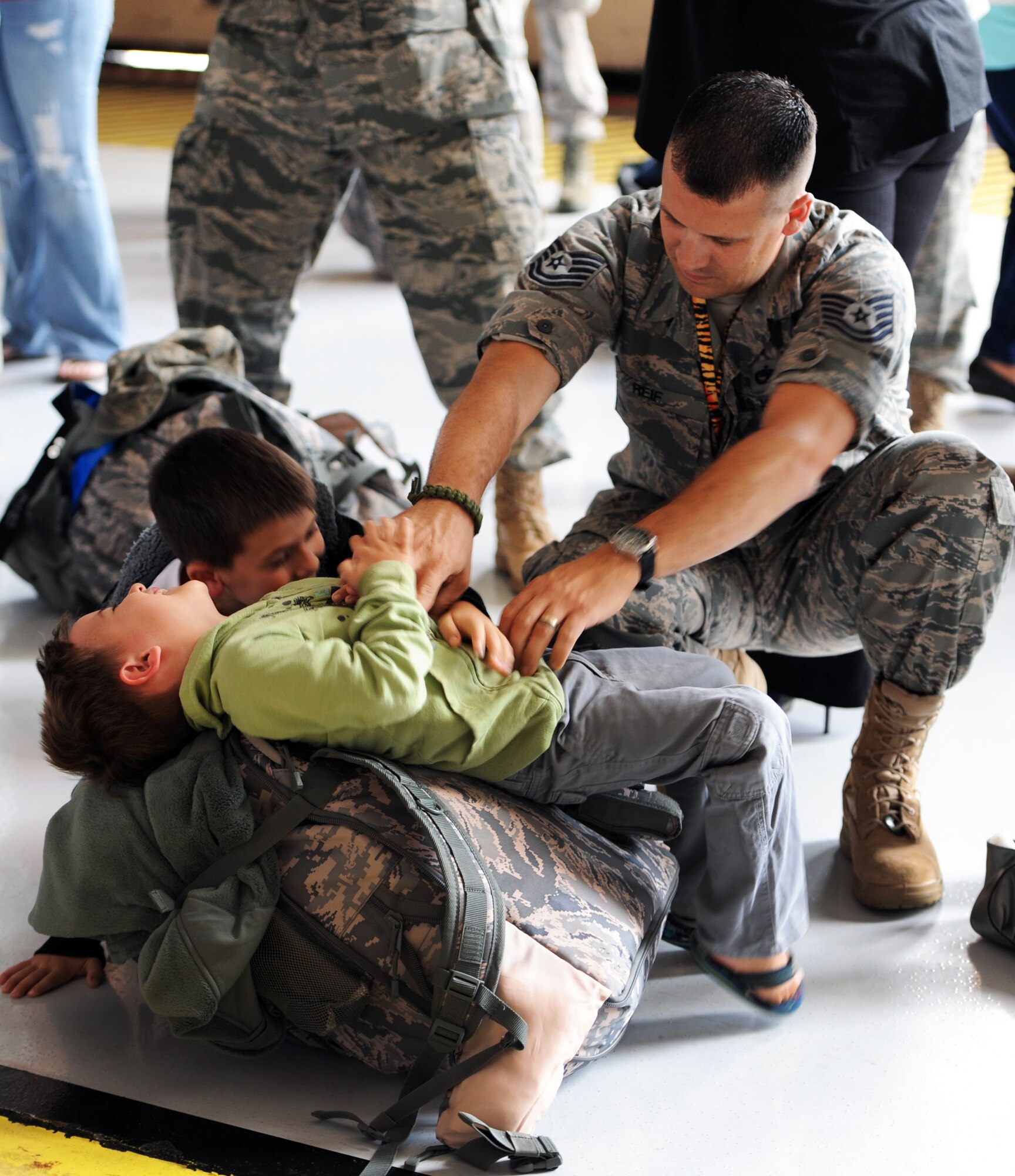 A U.S. Air Force 79th Fighter Squadron technical sergeant, plays with his children before deploying, Shaw Air Force Base, S.C., Sept. 19, 2011. Multiple squadrons gathered in Hanger 1200 with their fellow Airmen and family members before deploying. (U.S. Air Force photo by Tabatha Duarte/Released)
