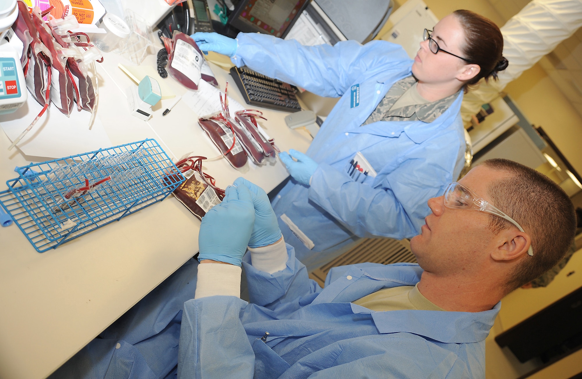 Airmen 1st Class Randall Cook and Elisa Malone, laboratory technicians, process in new blood units into the database and obtain samples for testing and storage at the David Grant Medical Center blood bank, Aug 30. (U.S. Air Force photo/ Staff Sgt. Liliana Moreno)