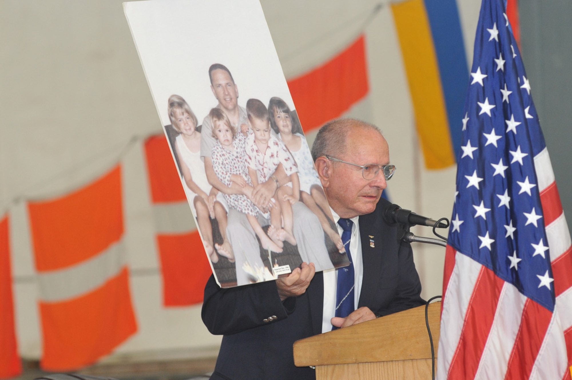 Cmdr. Allan R. Carpenter, U.S. Navy retired, shows a photo of the last time he saw his family before his F-4 Phantom II was shot down over North Vietnam Nov. 1, 1966. He spent the next seven years as a prisoner of war detainee in POW camps in and around Hanoi. Carpenter was the key note speaker during the Joint Base McGuire-Dix-Lakehurst POW/MIA Remembrance Ceremony Sept. 14 at Hanger 1 on Lakehurst. (U.S. Air Force photo by Wayne Russell/Released)