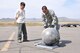 A local representative observes Tech. Sgt. John Lowe as he weighs a hydrogen fuel tank at the Chinngis Khaan International Airport, Mongolia, Aug. 26, 2011. Lowe was part of a 15-person Air Force Reserve crew that departed from March Air Reserve Base, Calif.,  on a mission to Mongolia to retrieve fallen satellite parts for NASA.  (U.S. Air Force photo/Master Sgt. Linda Welz)