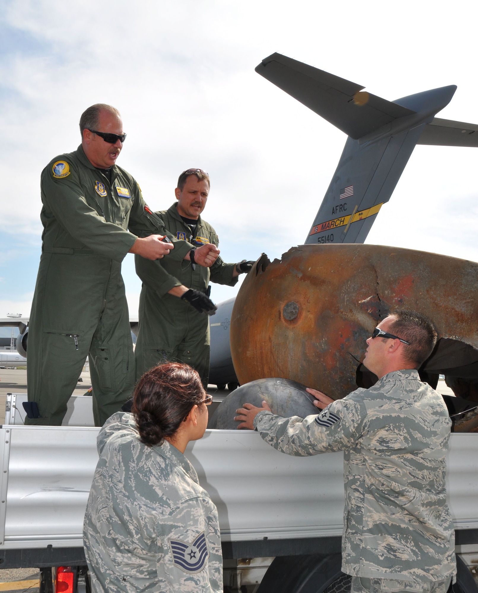 (clockwise from back left) Master Sgt. Lance Augustine, Tech. Sgt. Ronald Dunn, Tech. Sgt. John Lowe and Staff Sgt. Renee Young discuss a plan for loading expended rocket parts onto the C-17 Globemaster III, in Mongolia, Aug. 26, 2011.  The rocket parts had fallen to earth and landed in Mongolia last summer.  The March aircraft and crew were selected for the retrieval mission.  (U.S. Air Force photo/Master Sgt. Linda Welz)