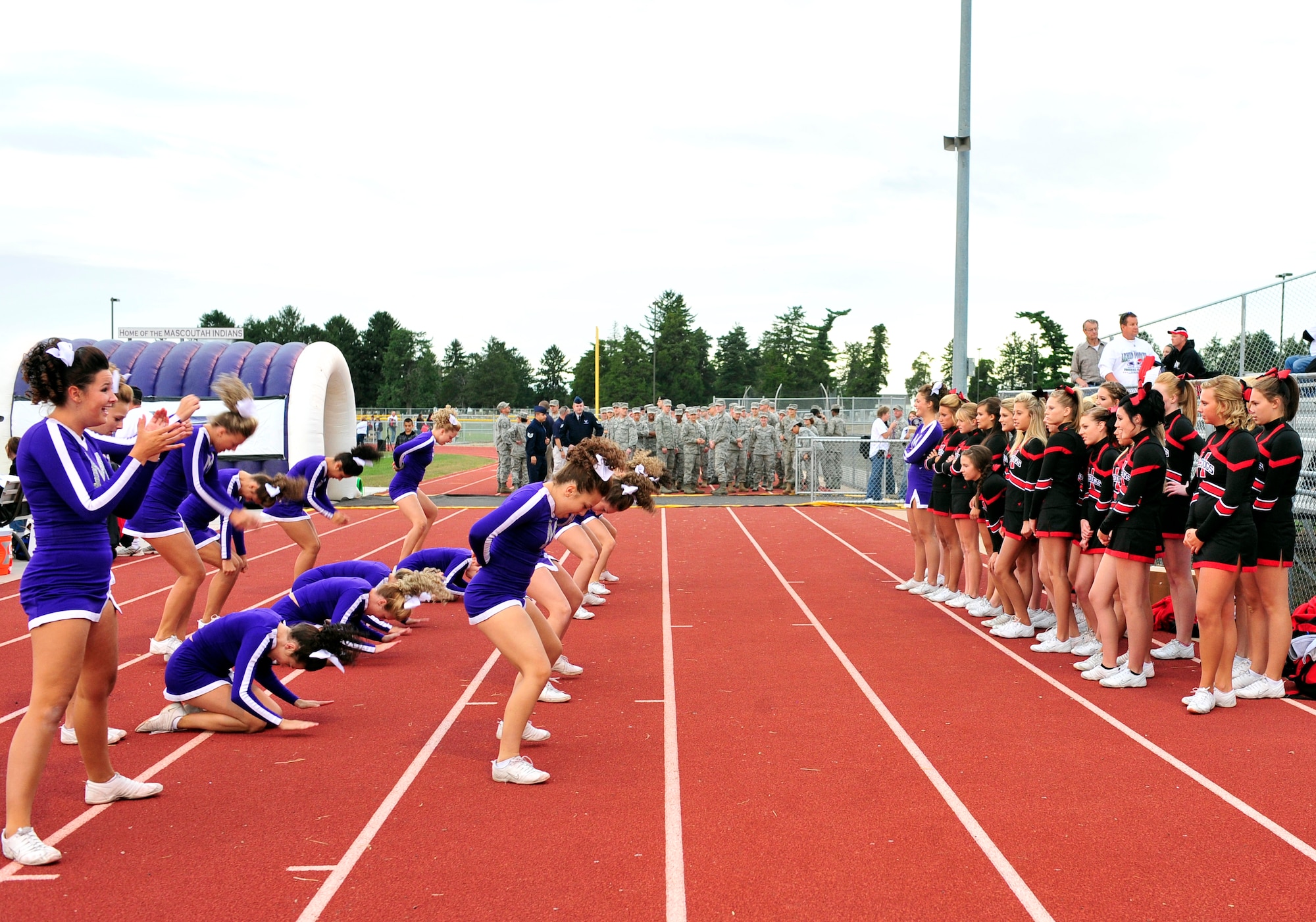 Team Scott members stand on the sidelines as cheerleaders from the Mascoutah Indians show off gymnastic skills to their rivalry squad of the Highland Bulldogs during the inaugural Annual Armed Forces Football Classic game Sept. 16, 2011 at Mascoutah High School Stadium. (U.S. Air Force photo/ Staff Sgt. Stephenie Wade)