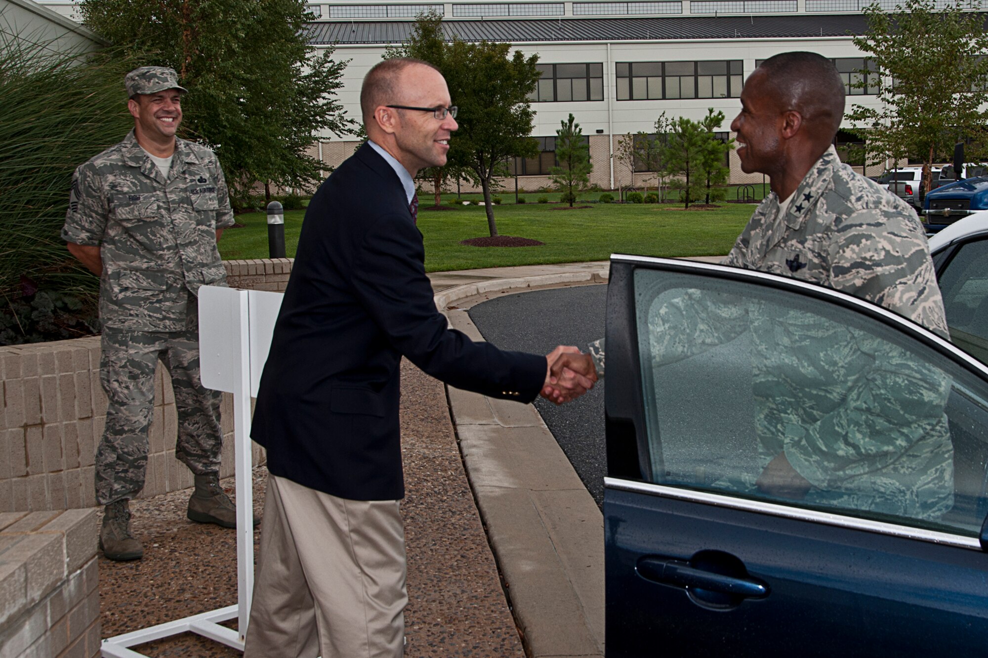 Trevor Dean, Air Force Mortuary Affairs Operations deputy, greets Maj. Gen. Darren McDew, Air Force District of Washington commander, with a handshake as the general arrives to Dover Air Force Base, Del. Sept. 8. Chief Master Sgt. David Fish, AFMAO chief enlisted manager, also greeted the general during his visit to the center, which has global responsibility for all Air Force mortuary matters for current and past conflicts, operates the nation's sole port mortuary and provides 24/7 global contingency mortuary response teams in support of Air Force requirements.