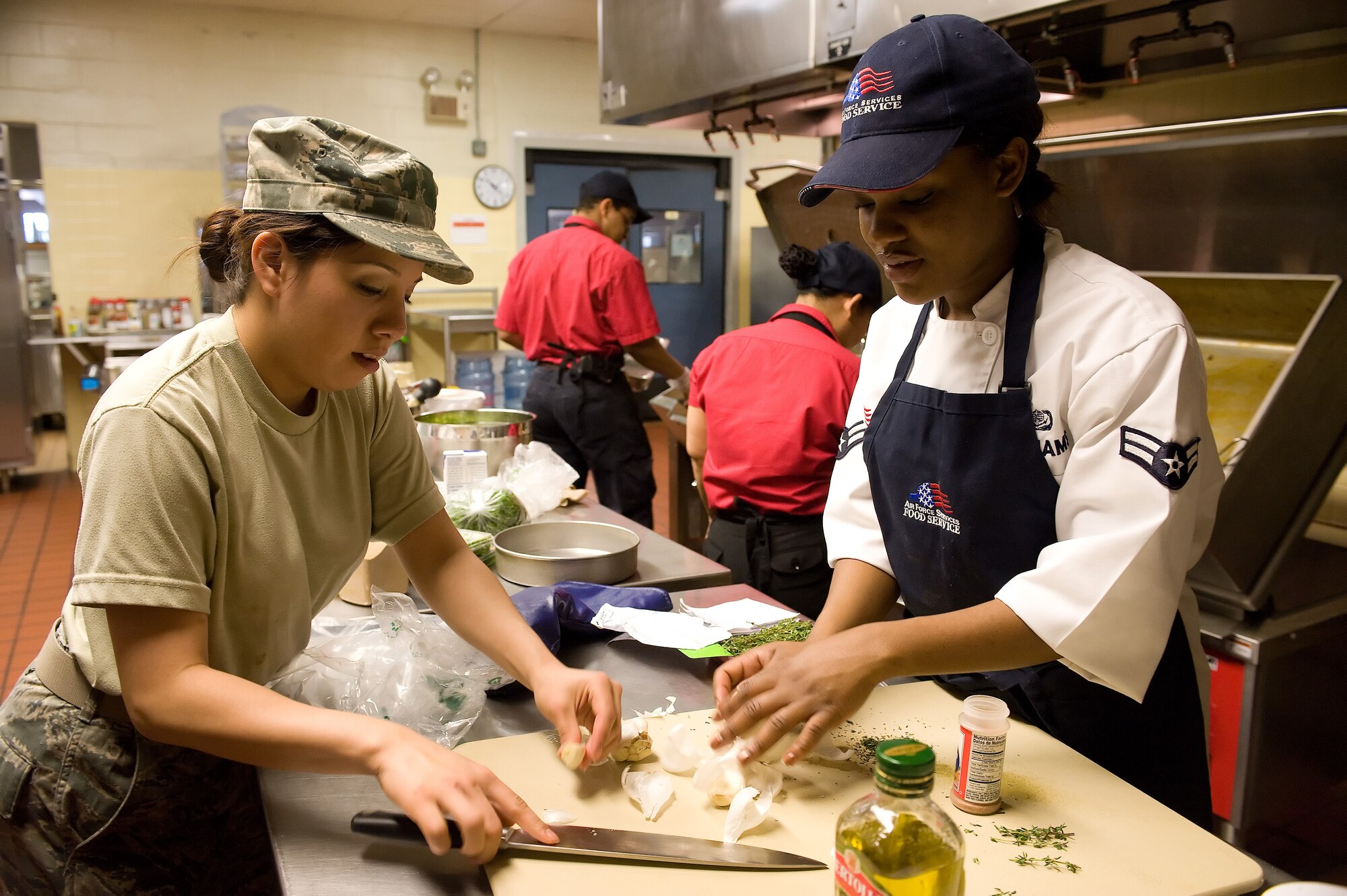 Airman 1st Class Naomi Martinez (left) and Airman 1st Class Raquell Williams, both food services technicians with the 436th Force Support Squadron, crush garlic in preparation for the Patterson Dining Facility’s Iron Chef Competition April 15, 2011 at Dover Air Force Base, Del. (U.S. Air Force photo by Adrian Rowan)