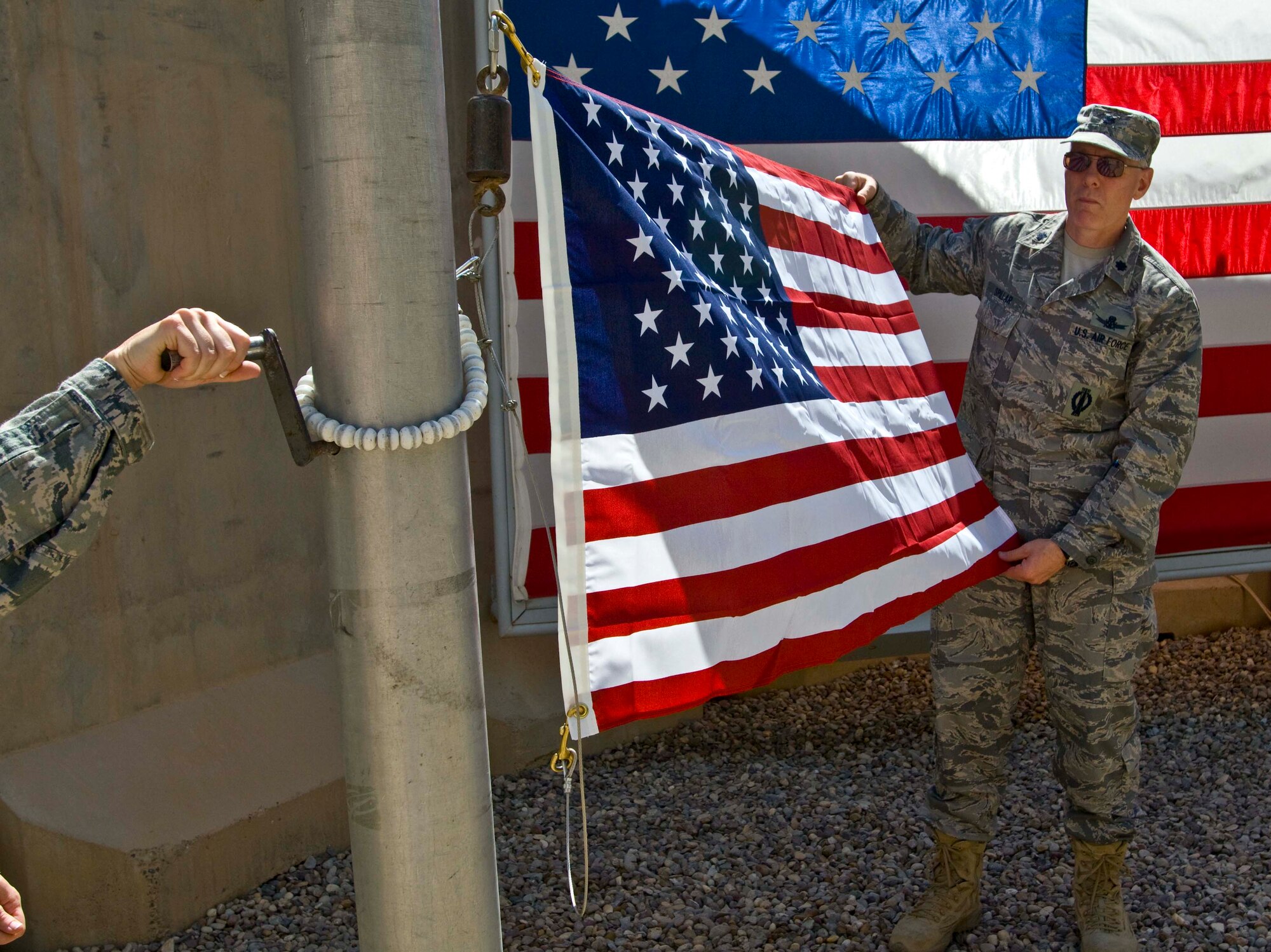 Lt. Col. Charles Spillar, deployed from AFOTEC Detachment 4, Peterson Air Force Base, presents the American flag prior to raising it in honor of the Air Force’s 64th birthday Sept. 18. Spillar currently serves as chief of the Sons of Iraq Division, J9, United States Forces, Iraq Strategic Communications, on the New Embassy Compound, Baghdad, Iraq.  (U.S. Army photo/Spc. Timothy Koster) 