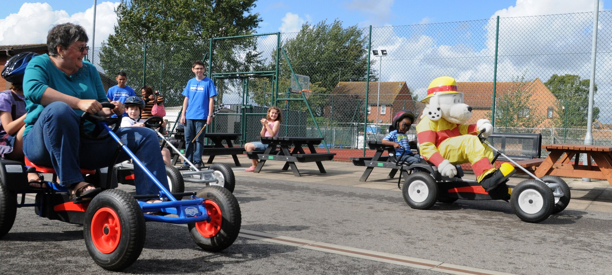 RAF MILDENHALL, England -- Sparky the Fire Dog races his pedal car against Jos Costello, wife of Allan Costello, 100th Force Support Squadron, and her daughter, Rachel, 8, at the Boys and Girls Clubs of America's Day for Kids at the youth center Sept. 17, 2011. The entertainment also included a magician and face painting. (U.S. Air Force photo by Staf Sgt. Thomas Trower)