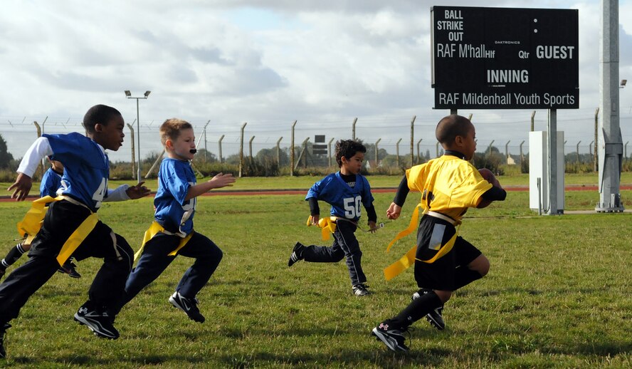 RAF MILDENHALL, England -- William Reed of the RAF Mildenhall Hornets, sprints for the end zone as defenders from RAF Lakenheath close in during a flag football game Sept. 17, 2011, at Heritage Park. The Hornets won this first youth sports flag football game of the season.  (U.S. Air Force photo by Staff Sgt. Thomas Trower)