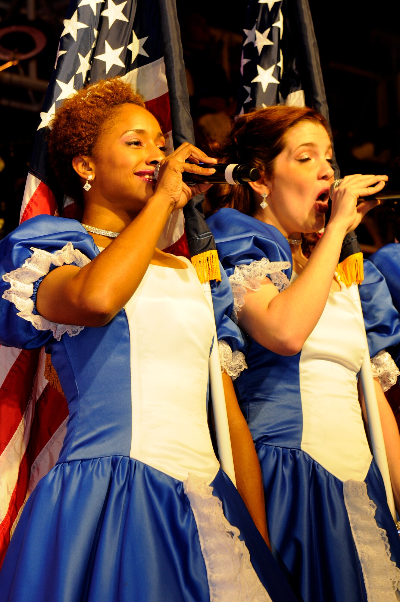 SPANGDAHLEM AIR BASE, Germany -- Air Force Tops in Blue vocalists Senior Airman Emerald Payne, left, 721st Aerial Port Squadron, Ramstein Air Base, Germany, and Airman 1st Class Aimee Grills, right, 354th Civil Engineer Squadron, Eielson Air Force Base, Alaska, sing for Spangdahlem service members and their families at the Skelton Memorial Fitness Center here Sept. 18. Tops in Blue is an active duty Air Force special unit made up of talented amateur performers selected for their entertainment abilities. The 2011 tour, “Rhythm Nation,” brings to life the music of America from the early 1900s through today. (U.S. Air Force photo/Airman 1st Class Brittney Frees)