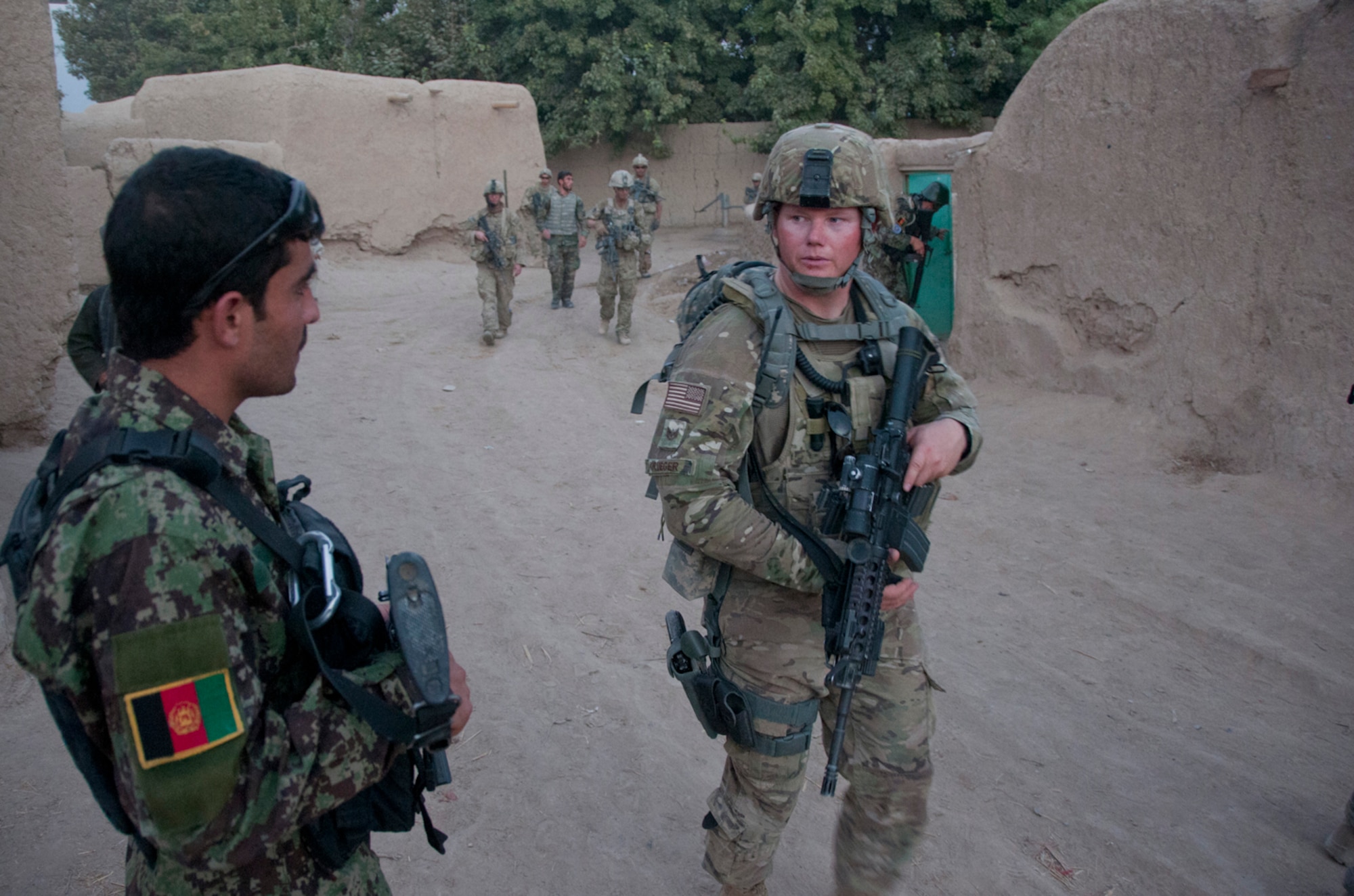 Tech. Sgt. John Krueger, security forces advisor, 738th Air Expeditionary Advisory Group, Kandahar Air Wing, walks past an Afghan Air Force security forces airman, Sept. 3, during an evening foot patrol in a village near Kandahar Airfield, Afghanistan. U.S. Air Force security forces airmen and soldiers from the 1st Squadron, 24th Infantry Division, conduct partnered patrols with Afghan airmen around the ground defense area to thwart threats against the airfield. Krueger is a Klamath Falls, Ore., native deployed from the 366th Security Force Squadron, Mountain Home Air Force Base, Idaho. (U.S. Air Force photo by Senior Airman Jessica Lockoski 


