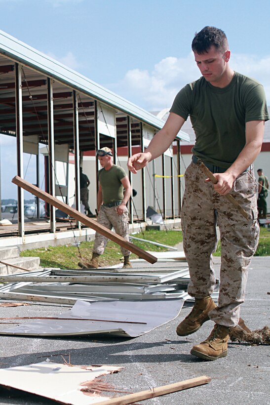 Marines gather materials while demolishing temporary buildings on the Marine Corps Air Station Futenma flightline Sept. 21. The buildings were constructed in 2006 and meant to be used as temporary workspaces. The Marines are assigned to Engineer Operations Company, Marine Wing Support Squadron 172, Marine Wing Support Group 17, 1st Marine Aircraft Wing, III Marine Expeditionary Force.