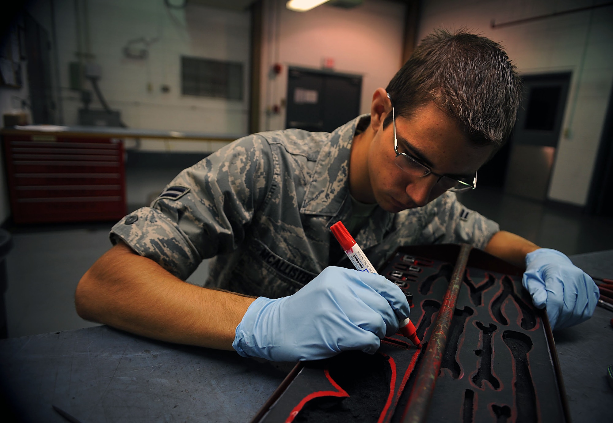 U.S. Air Force Airman 1st Class Zachary McAllister, 18th Component Maintenance Squadron Egress Systems apprentice, retraces precise  outlines to show exactly where each tool used by Egress Airmen go Sept. 20 at Kadena Air Base, Japan. Airmen working with Egress Systems provide first rate aircrew escape system maintenance for 54 assigned F-15C and D model aircraft at Kadena. This includes arming, de-arming, removing, inspecting and installing Advanced Concept Ejection Seats (ACES II), parachutes, survival kits, and 3600 explosive batteries, initiators, detonating cords, and rockets involved in the swift and safe ejection of fighter aircrew here at Kadena. (U.S. Air Force photo by Senior Airman Sara Csurilla)