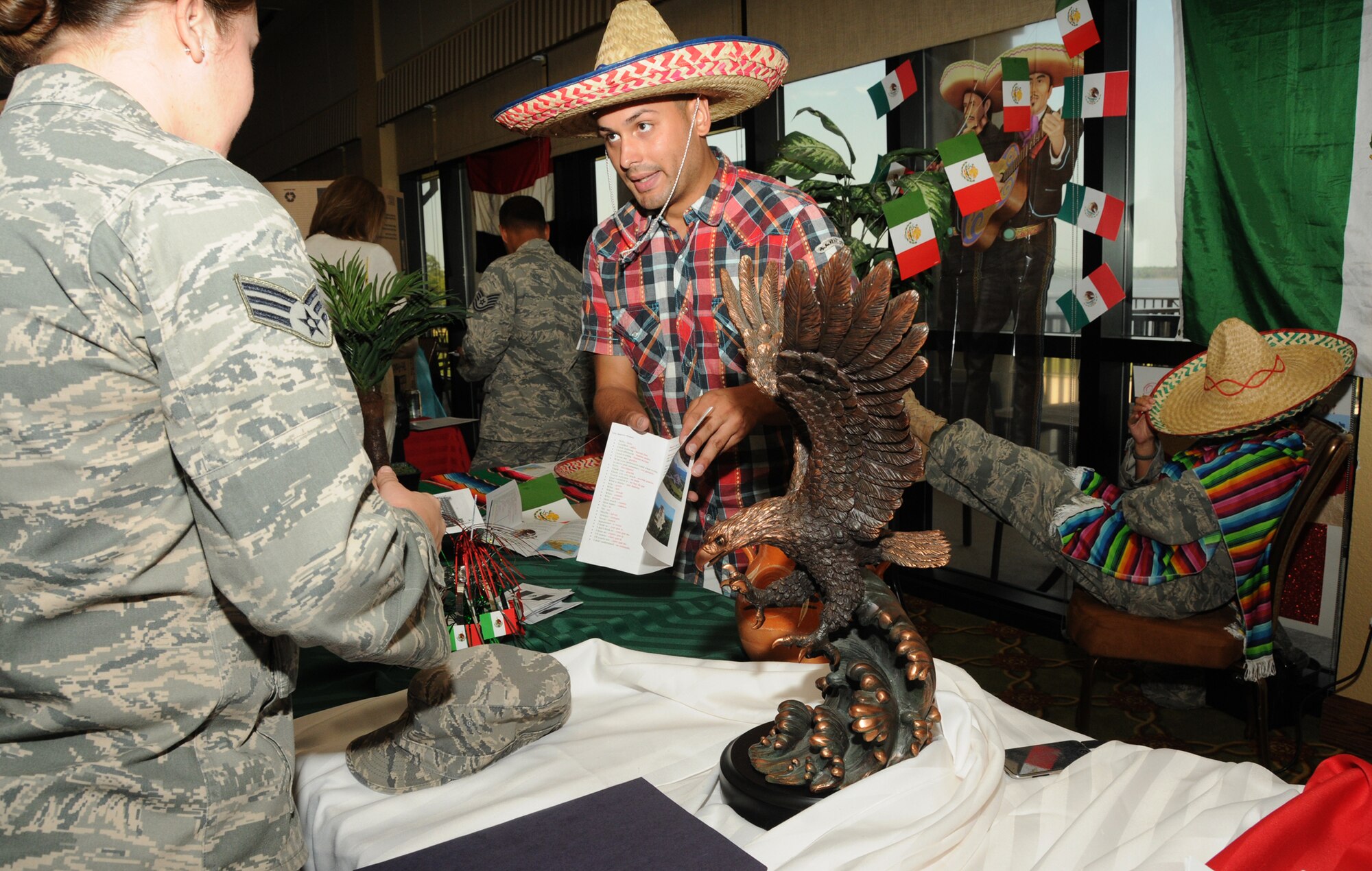 Senior Airman Ashley Jordan, left, 81st Aerospace Medicine Squadron, gives Airman 1st Class Anthony Acevedo, 81st Force Support Squadron, some literature about Mexico as Staff Sgt. Lucinda Barrera, 81st FSS, takes a siesta under her sombrero in the background at Diversity Day, Sept. 13 at the Bay Breeze Event Center.  The cultural celebration also included music, dancing, poetry, face painting, games and food for children and adults.    (U.S. Air Force photo by Kemberly Groue)