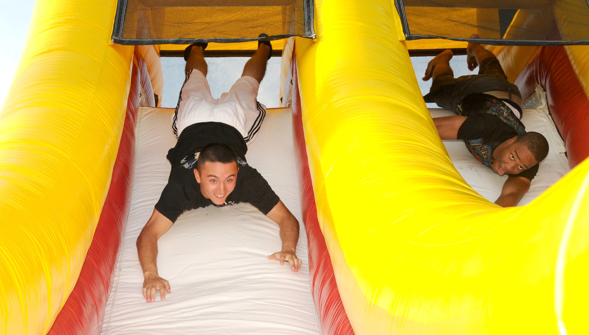 Airmen Basic David Polojac, left, and Orion Whiters, 338th Training Squadron students, race through an inflatable obstacle course at the Air Force birthday party on the parade grounds Sept 16. The event offered live music, food, beverages, games, contests and prizes.  (U.S. Air Force photo by Kemberly Groue)