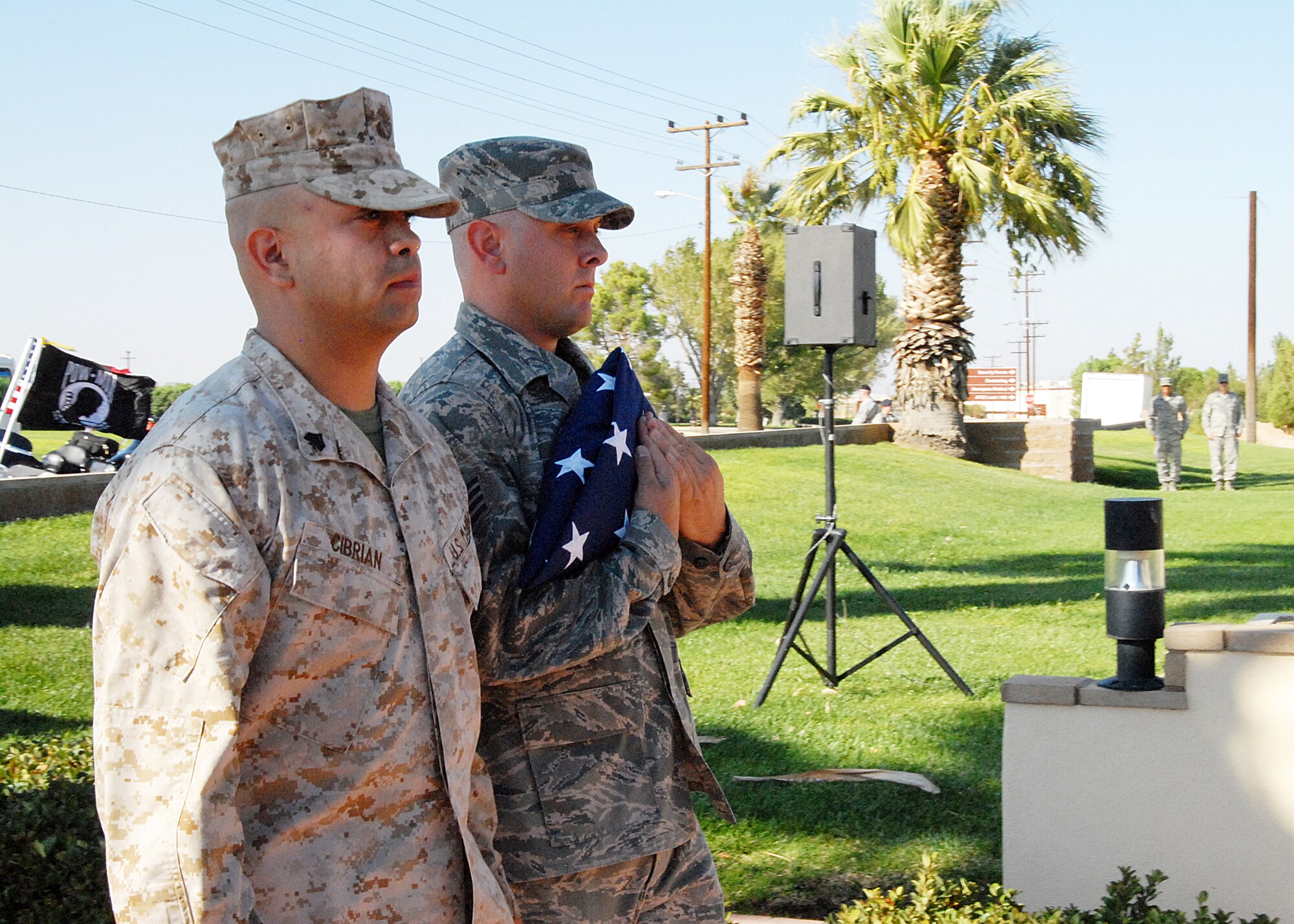 Marine Sgt. Jeff Cibrian, Marine Aircraft Group 41, and Staff Sgt. Jason Minor, 95th Comptroller Squadron, stand at attention after receiving the folded flag during the POW/MIA Day retreat ceremony. (Air Force photo by Diane Betzler)
