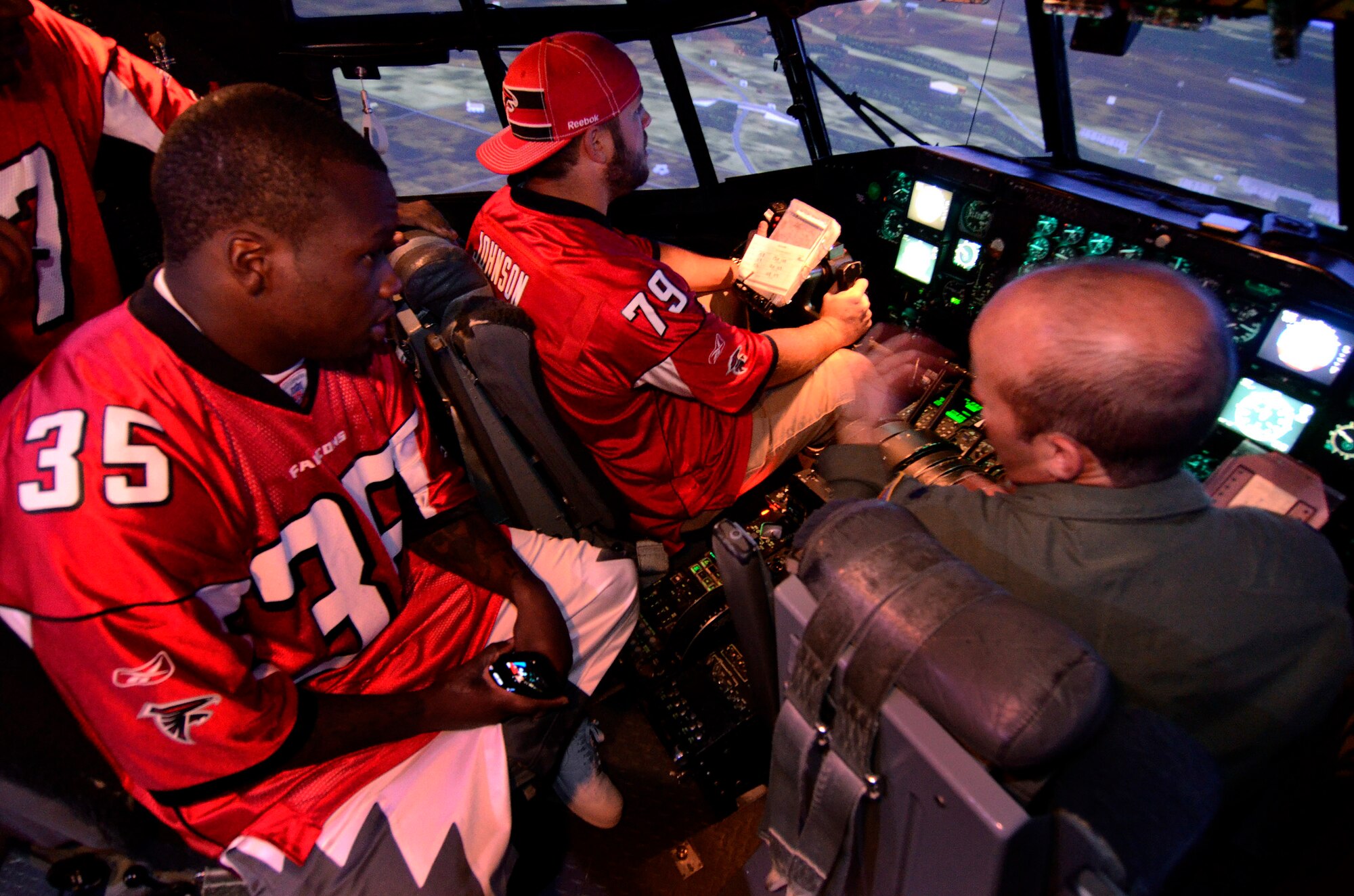 Mike Johnson, a guard with the Atlanta Falcons football team flies the C-130 flight simulator with running back, Antone Smith looking on from the flight engineers seat, at Dobbins Air Reserve Base, Sept. 20. The football team members came to Dobbins to show their appreciation for what the military does every day.   (U.S. Air Force photo/ Brad Fallin)