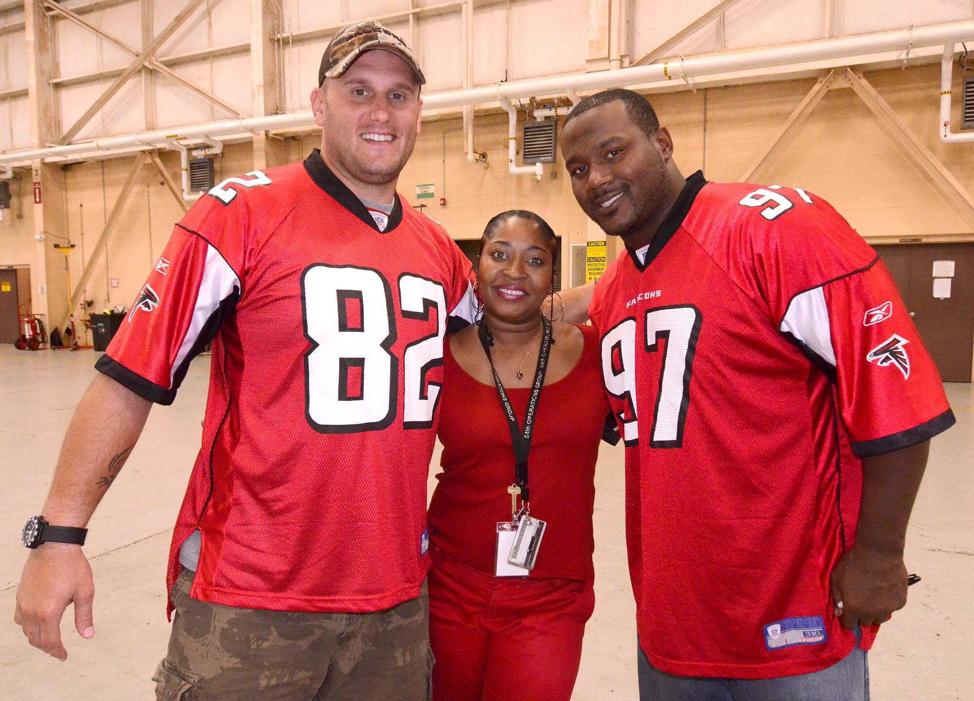 Lena Bell, from 94th Operations Group administrative assistant, poses with Joe Zelenka, tight end, and Carlton Powell, defensive tackle of the Atlanta Falcons at Dobbins Air Reserve Base, Sept. 20. The football team members came to Dobbins to show their appreciation for what the military does every day.   (U.S. Air Force photo/ Brad Fallin)