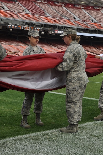 California Air National Guardsman Senior Airman Karen Gaetos from the 129th Rescue Wing, Moffett Federal Airfield, Calif., and an Airman from Travis Air Force Base, Calif., participate in a flag ceremony in rememberance of the Sept. 11th terrorist attacks, Candlestick Park, San Francisco, Calif., Sept. 11, 2011.  Approximately 200 Airmen from the 129th Rescue Wing and from Travis Air Force Base took part in the ceremony.  (Air National Guard Photo by Airman 1st Class John Pharr)