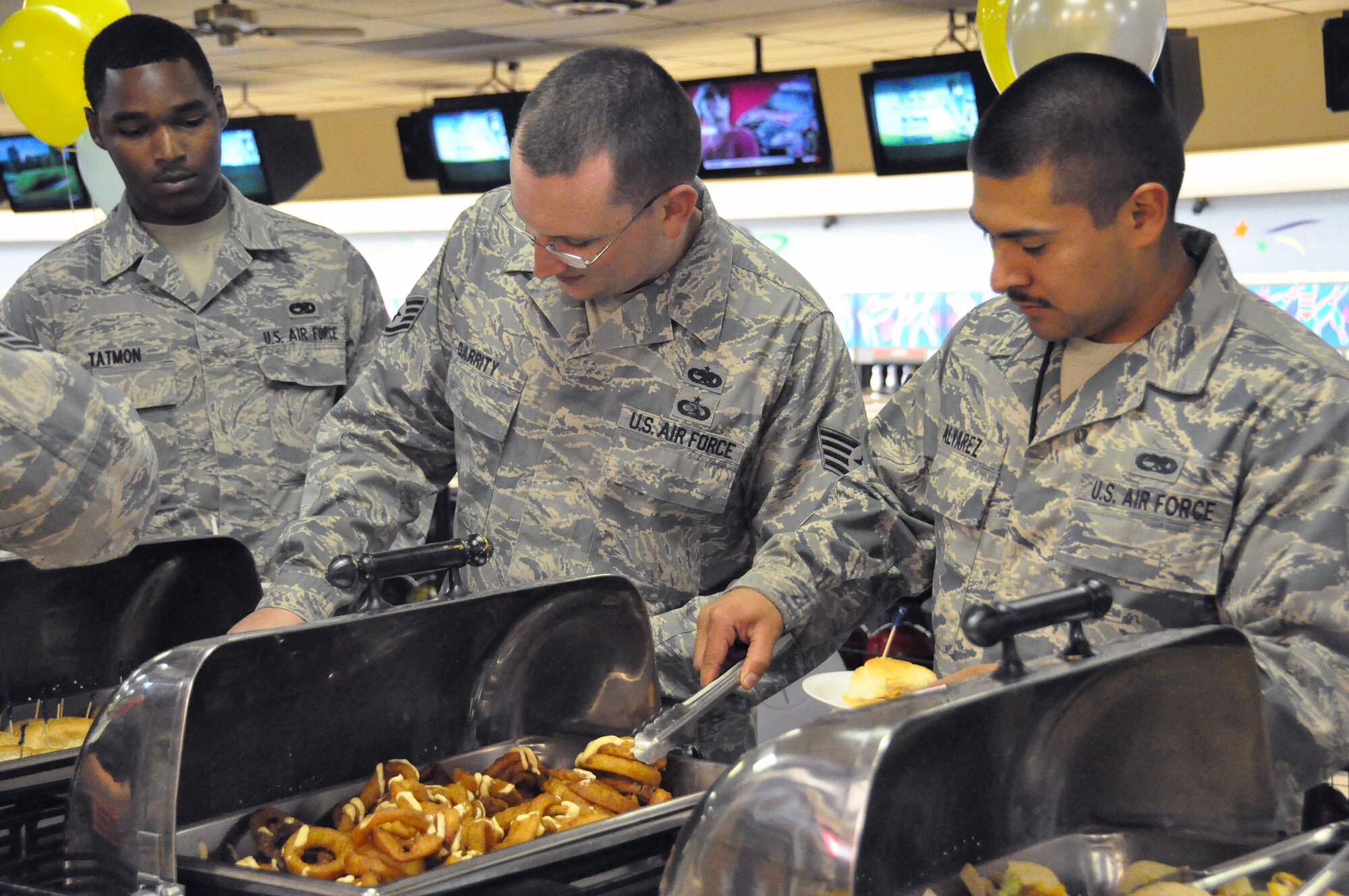 Airman 1st Class Harold Tatmon, Staff Sgt. Sean Garrity and Senior Airman Samuel Alvarez from the 60th Maintenance Group line up at the grand opening of Ten Pin Sept. 15 for a taste of some of the unique menu items that the newest Food Transformation Initiative location will be serving. (U.S. Air Force photo/ Airman Madelyn Ottem)