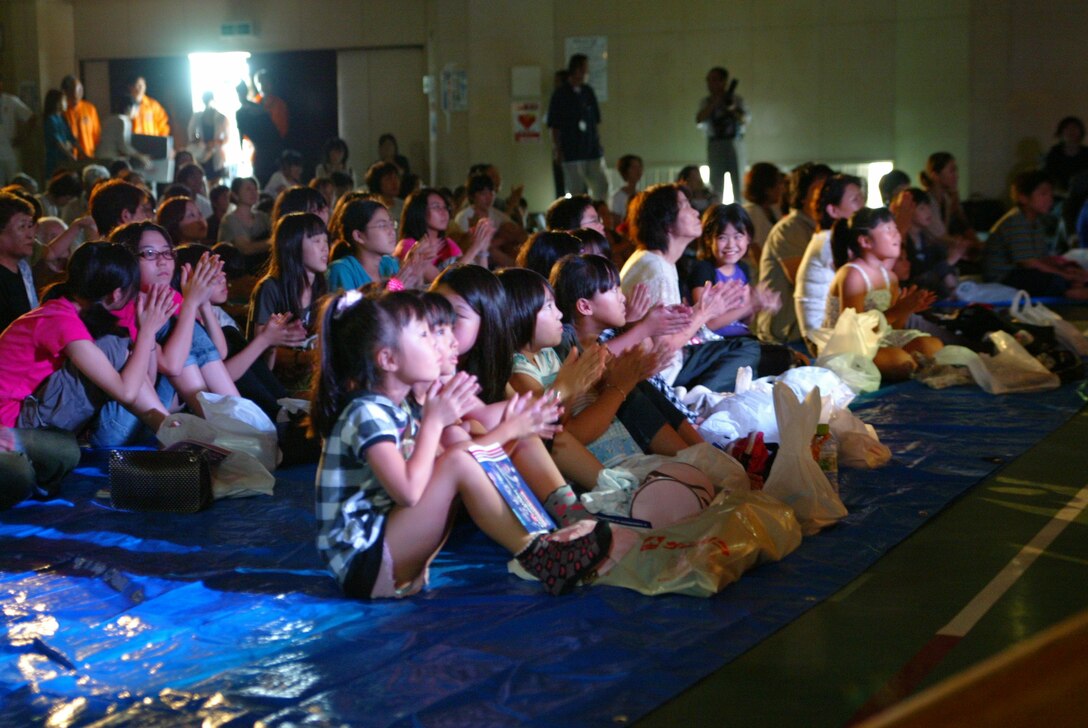 Audience members gather in a gym that was used to house tsunami/earthquake refugees during the disaster.