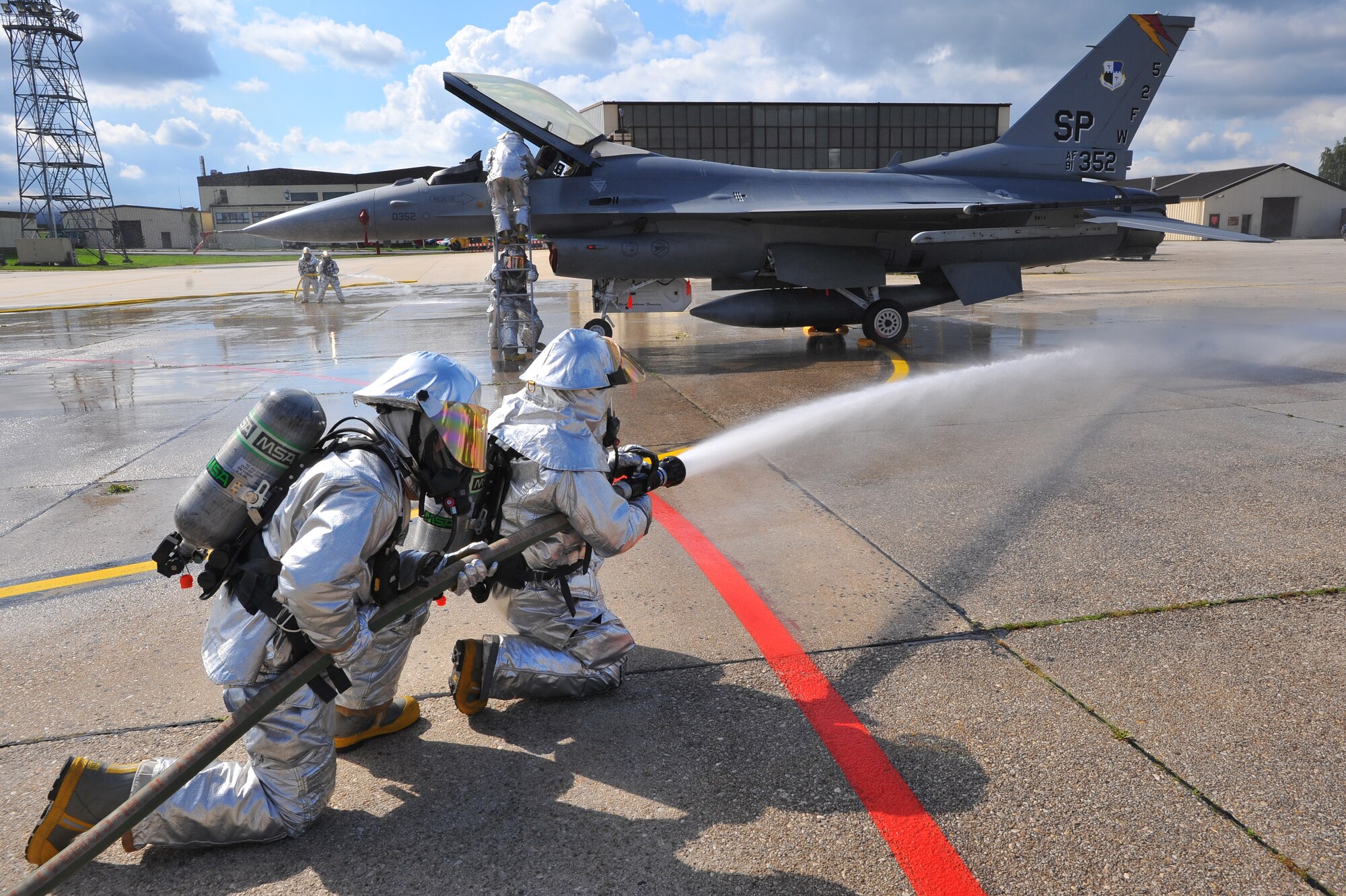 SPANGDAHLEM AIR BASE, Germany – Airmen assigned to the 52nd Civil Engineer Squadron Fire Department, simulate extinguishing an aircraft fire while rescuing a trapped pilot during a capabilities demonstration for 52nd Fighter Wing leadership here Sept. 19. The demonstration showcased the fire department’s ability to protect Airmen and assets. (U.S Air Force photo/Airman 1st Class Dillon Davis)