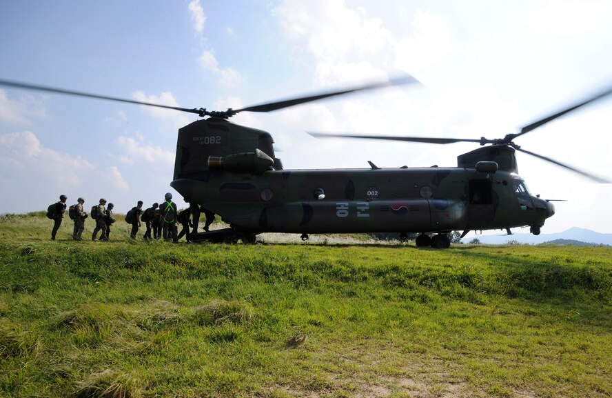 CHEONGJU, Republic of Korea -- A U.S. Air Force survival, evasion, resistance and escape instructor along with Republic of Korea Air Force instructors rush aboard ROKAF Chinook helicopter here Sept. 15. The U.S. Air Force and ROKAF performed a jump together helping improve relationships with one another and stimulate a continued bilateral partnership on the peninsula. (U.S. Air Force photo/Staff Sgt. Rasheen A. Douglas)