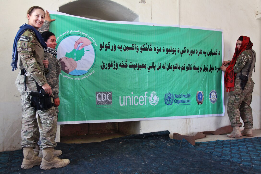U.S. Army 1st Lt. Sarah Casper, left, and Capt. Katherine Redding, right, hang a poster promoting vaccines at the district center in Spin Boldak City, Kandahar province, Afghanistan, Sept. 18, 2011. Casper and Redding are assigned to the 504th Battlefield Support Brigade.
