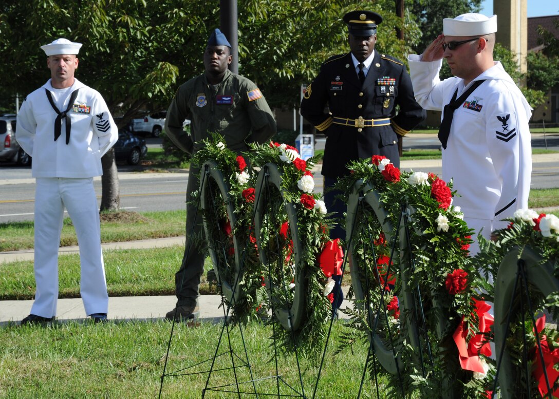 Navy Petty Officer 2nd Class Mathew Mustico, Naval Air Facility Washington administrative legal clerk, salutes to honor the Coast Guard during a POW/ MIA Remembrance Day ceremony Sept. 16 at the Airmen Memorial Museum in Suitland, Md. Each of the five wreaths represented Prisoners of War and Missing in Action service members from each branch of service. (U.S. Air Force photo/Airman 1st Class Bahja J. Jones)