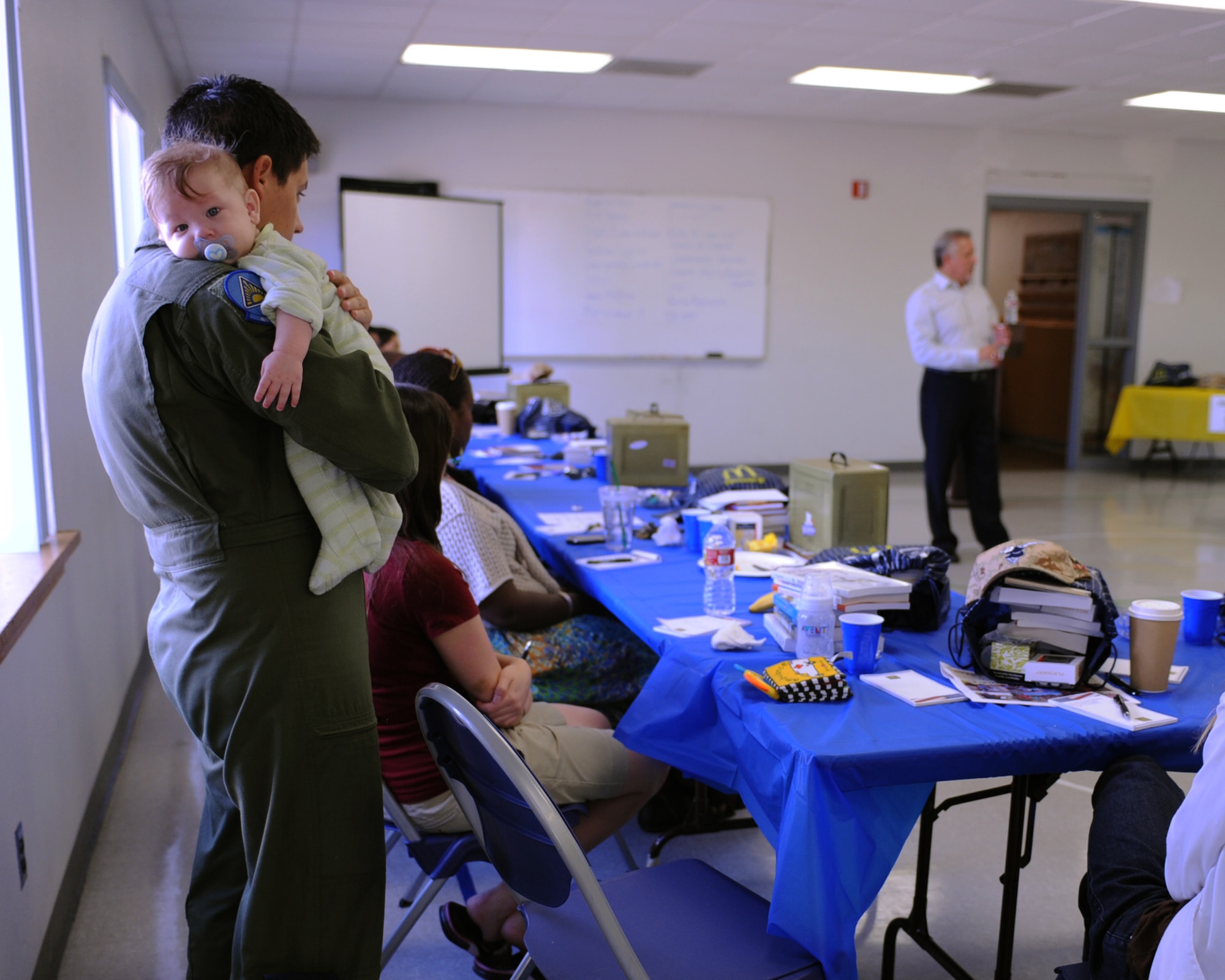 DAVIS-MONTHAN AIR FORCE BASE, Ariz. – Senior Airman Christopher Shishido, 41st Electronic Combat Squadron, holds his son, Joshua Shishido, as he listens to the financial briefing given by Mr. Frank Molinar,  Military & Family Life Consultants, certified financial planner, at the Operation COPE Roadshow here Sept. 16. The COPE Roadshow was developed as way to provide sustained support and resiliency training for our Airmen and their families. (U.S. Air Force photo/Airman 1st Class Christine Halan)
