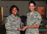 Chief Master Sgt. Bionca Lindsey awards Airman 1st Class Sarah Rodriguez with the Chief's Group Superior Performer award during the chief’s group meeting, Aug. 2, 2011. Rodriguez contributed to the 4th Medical Group’s (MDG) excellent rating on their Health Services Inspection by compiling thousands of documents and correcting potential errors in medical records. Rodriguez also completed her five-level upgrade training four months ahead of schedule and is working towards completing her Community College of the Air Force degree. Lindsey is the 4th MDG superintendent from Chicago and Rodriguez is an aerospace medicine technician with the 4th Aerospace Medicine Squadron and hails from Brownsville, Texas. (U.S. Air Force photo by Senior Airman Marissa Tucker)