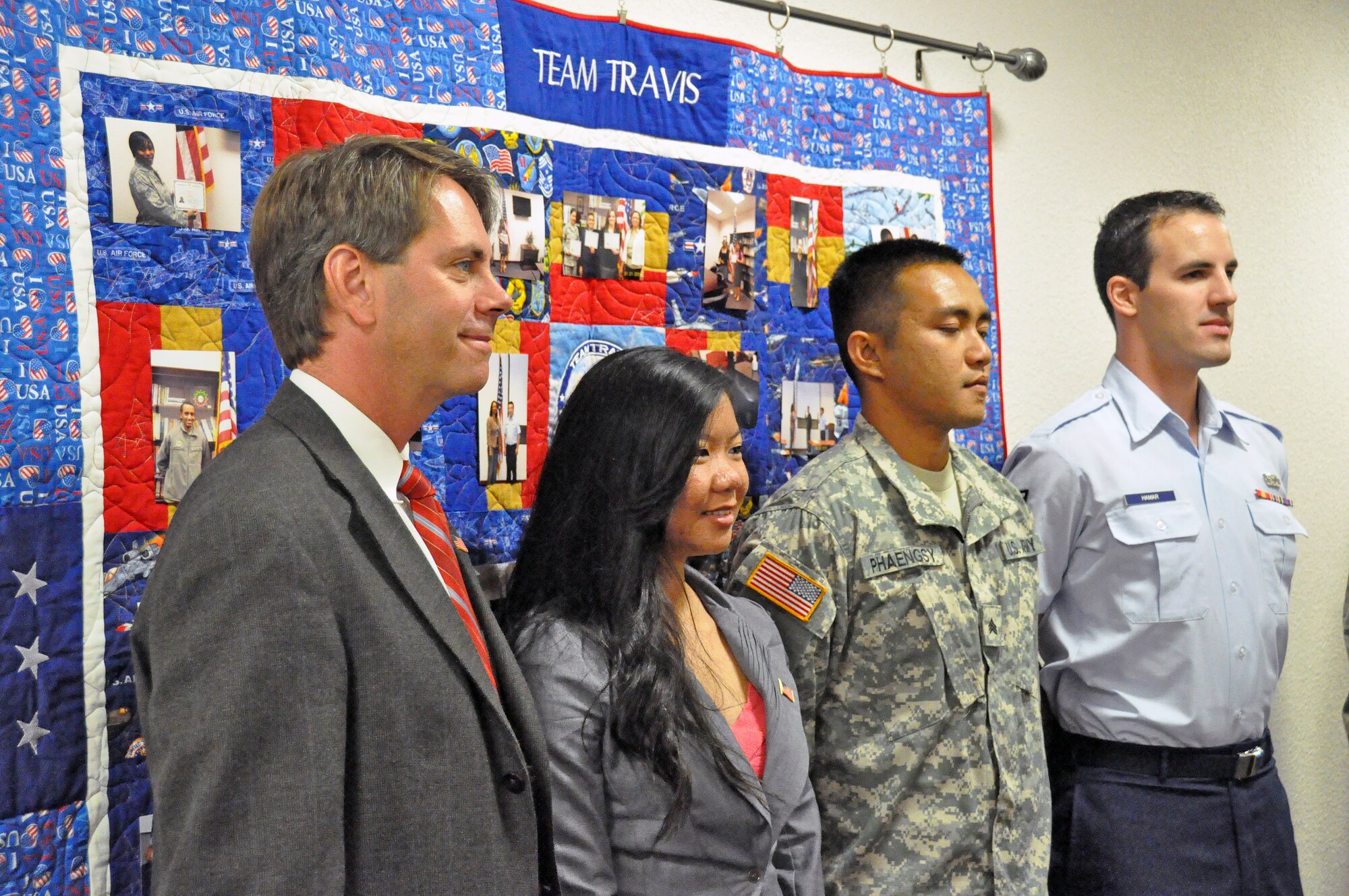 Michael Biggs, U.S. Department of Homeland Security office director, stands with the three new naturalized citizens, Navy Petty Officer 3rd Class Jeanne Olivo, Army Sgt. Chansophru Phaengsy and Senior Airman Adam Hamar in front of the Naturalization Quilt Dedication Sept. 16 at the Airman and Family Readiness Center after their own Naturalization Ceremony. (U.S. Air Force photo/ Airman Madelyn Ottem)