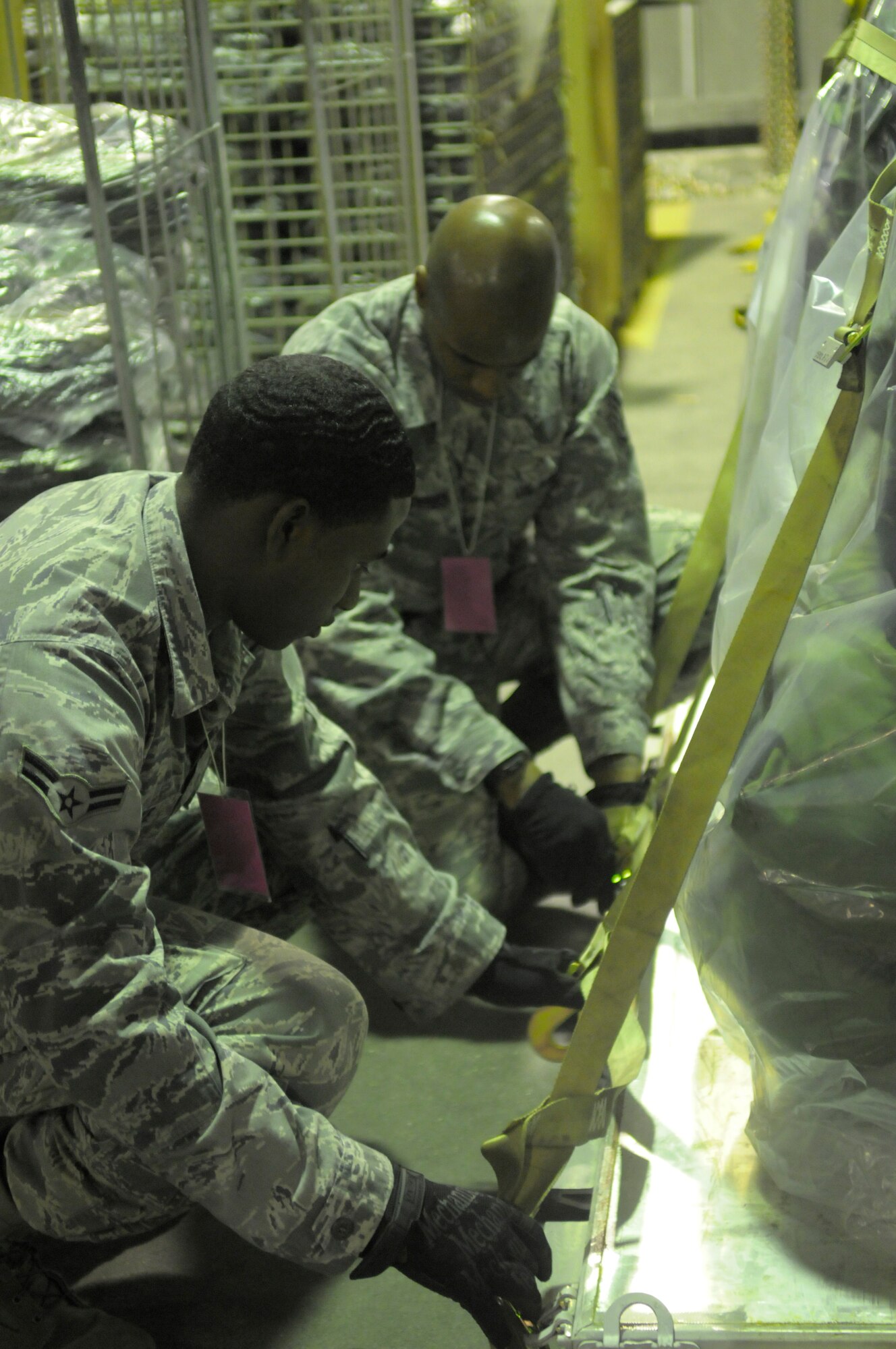 Airman 1st Class Andrae Blake, 31st Dental Squadron dental assistant, and Staff. Sgt Johnni Anderson NCO in charge of periodontics ensure the security of a pallet during an operational readiness exercise Sept. 21 at Aviano Air Base, Italy. Blake and Anderson are part of the cargo deployment function team. (U.S. Air Force photo/Airman 1st Class Briana Jones)