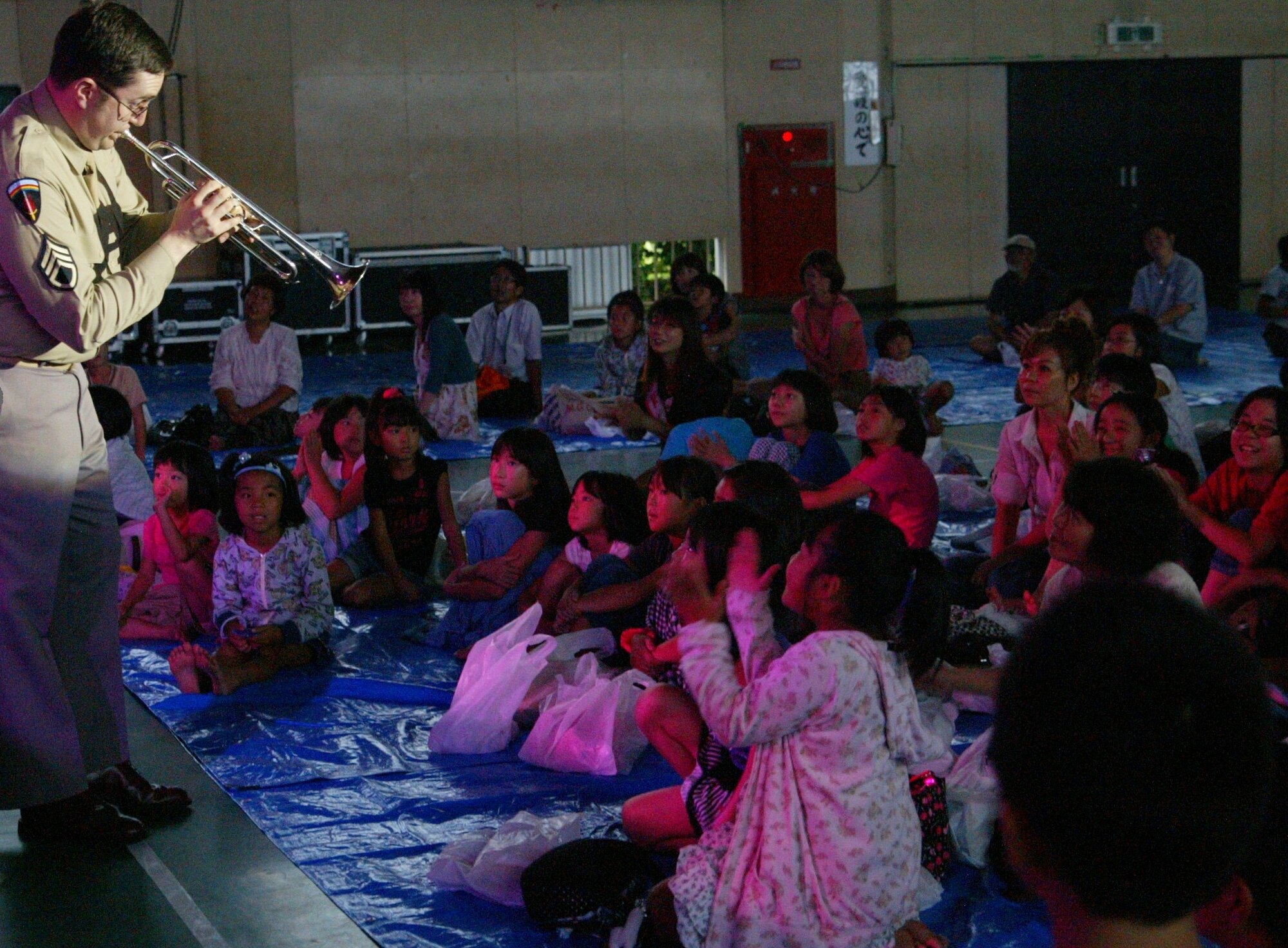 SENDAI, JAPAN-- SSgt Tom Salyers demonstrates the trumpet up close to curious children during a performance in a gymnasium.  Sep 2011. (courtesy photo)