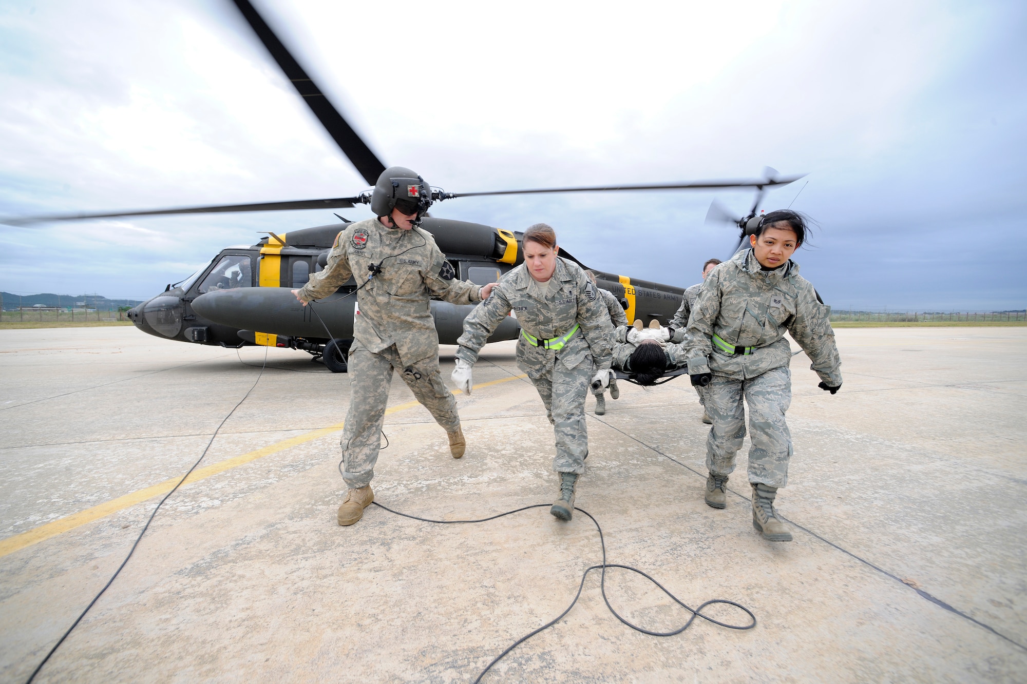 KUNSAN AIR BASE, Republic of Korea -- Army Spc. James Donnel, a flight medic with C Co. 3/2 General Support Aviation Battalion at Camp Humphreys, guides members of the 8th Medical Group with a patient to a UH-60 Blackhawk helicopter during their medical evacuation training here Sept. 19. Army flight medics from Camp Humphreys visited the Wolf Pack to familiarize the medics with the medevac concept. (U.S. Air Force photo/Staff Sgt. Rasheen A. Douglas)