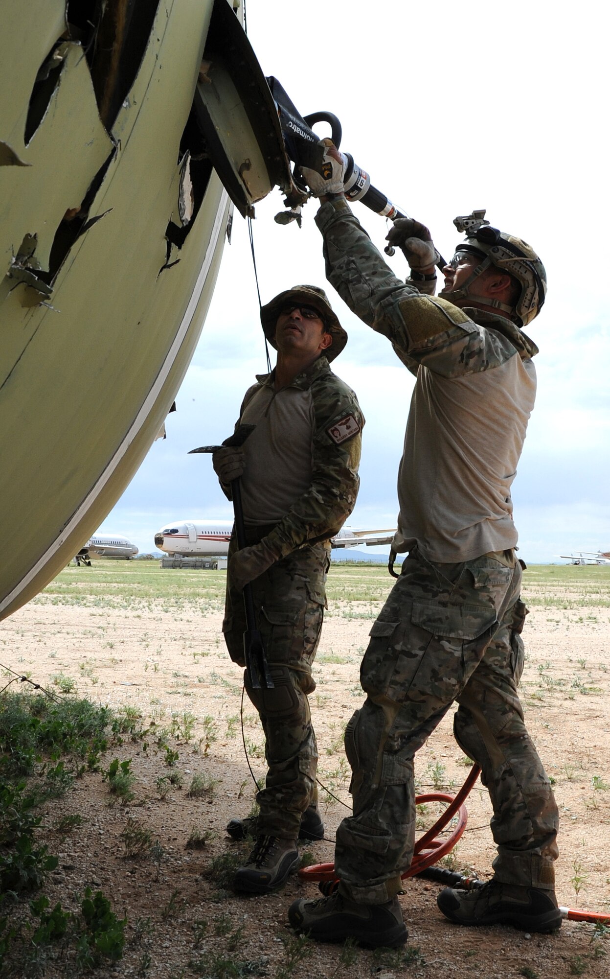 Staff Sgt. Ryan Gilbert, a pararescueman with the 306th Rescue Squadron, utilizes the Jaws of Life to cut into a C-130 Hercules as Capt. Ricardo Montana, 306th RQS combat rescue officer, observes during the unit’s ROCO training exercise. Pararescuemen with the 306th RQS practiced extraction techniques on a C-130 inside the “bone yard” at Davis-Monthan Air Force Base, Ariz. (U.S. Air Force Photo/ Tech. Sgt. Luke Johnson)