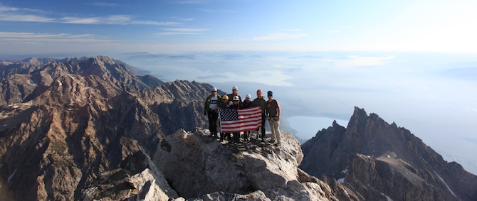 The Veterans Expeditions 9/11 Summit to Remember team pose for a photo while holding the American Flag on the summit of the Grand Teton Sept. 11. The team members are Nick Watson, Army veteran; Aaron Plant, Navy veteran; Stacy Bare, Army veteran; Dana Miemela, Navy veteran; Steve Hitchcock, Army veteran; Chad Butrick, Army veteran; and 1st Lt. Jared Rund, 90th Logistics Readiness Squadron.