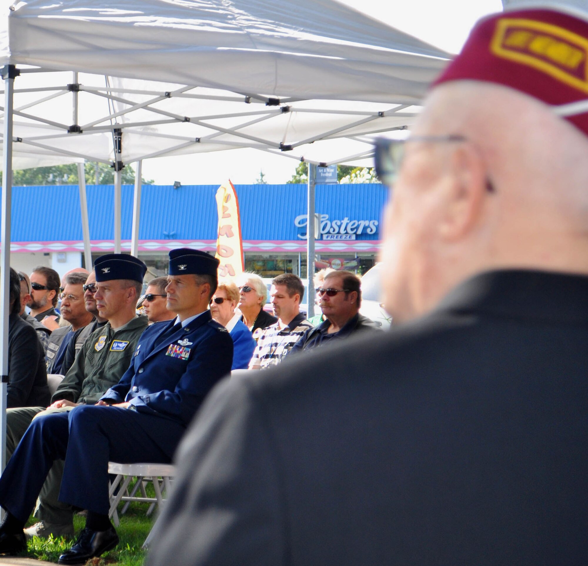 TRAVIS AIR FORCE BASE, Calif. --Col. Al Lupenski, in blues, listens to Mel Raimundo speak about his experience as a prisoner of war, at the Sept. 16, 2011 observance of National POW/MIA Recognition Day, in Vacaville, Calif. The 349th Operations Group commander, the colonel joined other Travis leaders and Airmen to honor POWs and missing in action heroes, of which 83.000 remain unaccounted for since World War II through the Cold War. Raimundo, an ambulance driver, spent five months in Stalag 4B, in Germany, from 1944 to 1945. (U.S. Air Force photo/Senior Master Sgt. Ellen L. Hatfield)