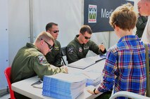 1st Lt. David Brandon, Capt. John Stukavec and 1st Lt. Derrick Torres, all pilot trainees from the 4th Training Squadron, sign autographs and answer questions during the Duxford Air Show in Cambridgeshire, England, Sept. 3, 2011. The air show celebrated the 70th anniversary of the formation of the Royal Air Force Eagles Squadrons and the 75th anniversary of the Supermarine Spitfire aircraft, which was flown by American volunteers during World War II. (U.S. Air Force photo by Senior Airman Marissa Tucker)