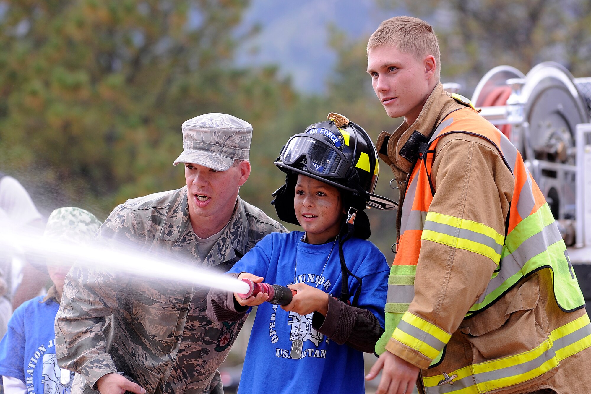 Giovanni Del-Pontone, 8, tests out a fire hose, with the help of Staff Sgt. Travis Barrett and Airman 1st Class Everett Cowart, both firefighters from the 10th Civil Engineer Squadron.   (U.S. Air Force Photo/Mike Kaplan)